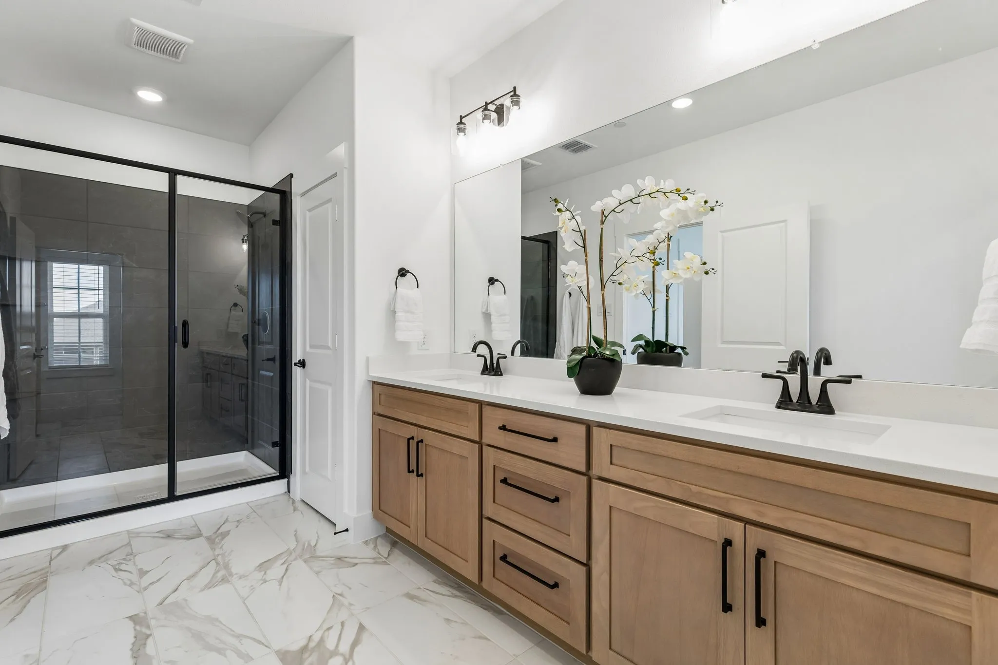 Dual vanity with light wood-finish cabinetry and white countertops