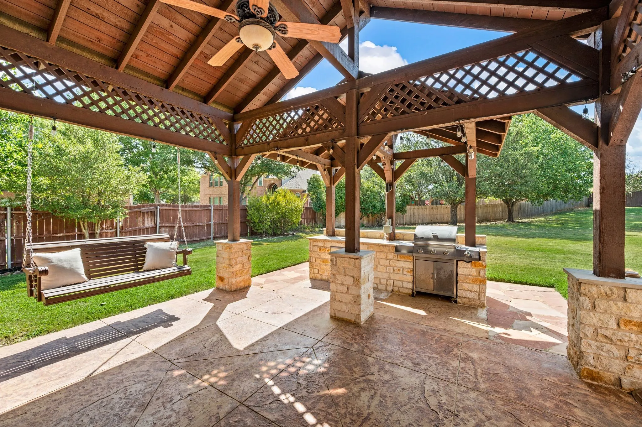 Expansive covered patio featuring a wood-finish ceiling, ceiling fan, and built-in grill