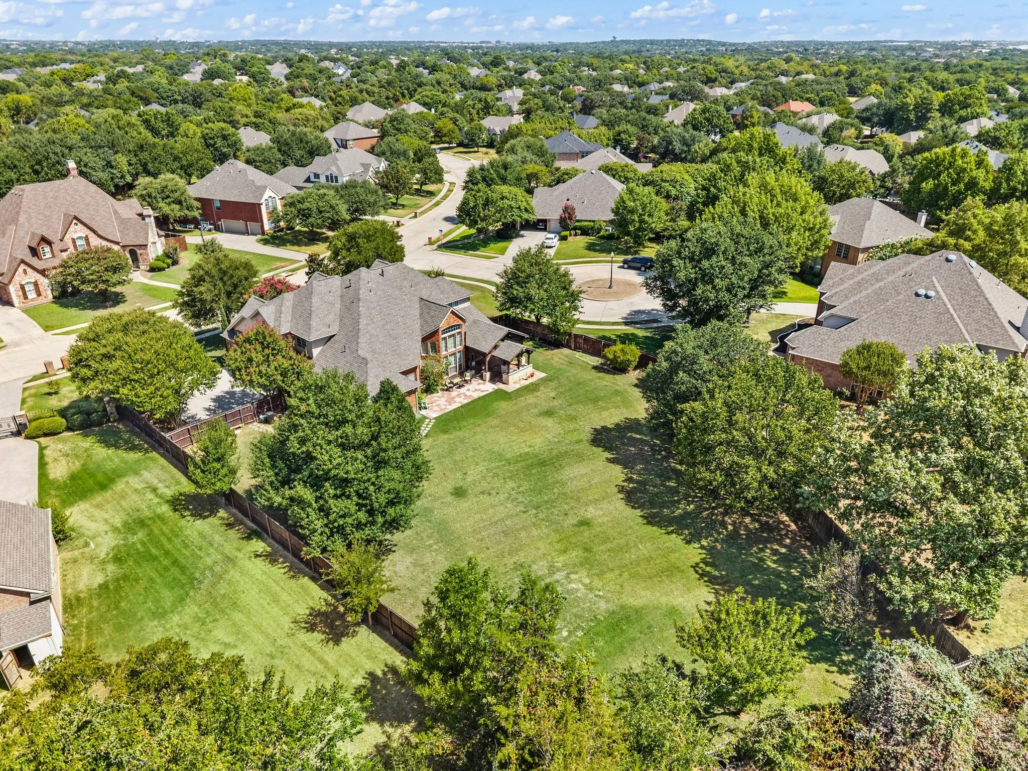 Spacious lot with a manicured lawn, established trees, and surrounding fencing