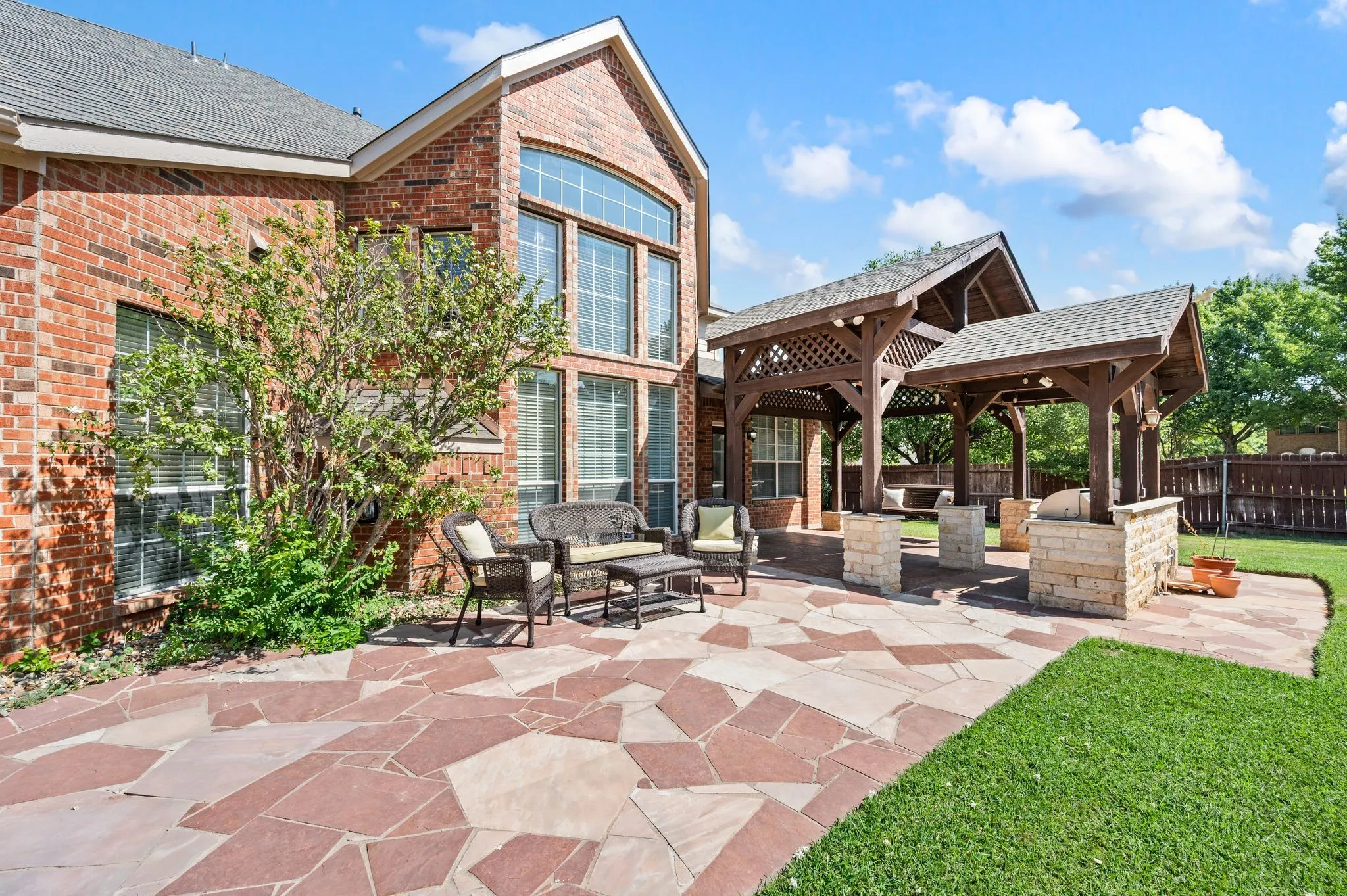 Expansive flagstone patio with a covered outdoor kitchen and a separate covered pergola structure