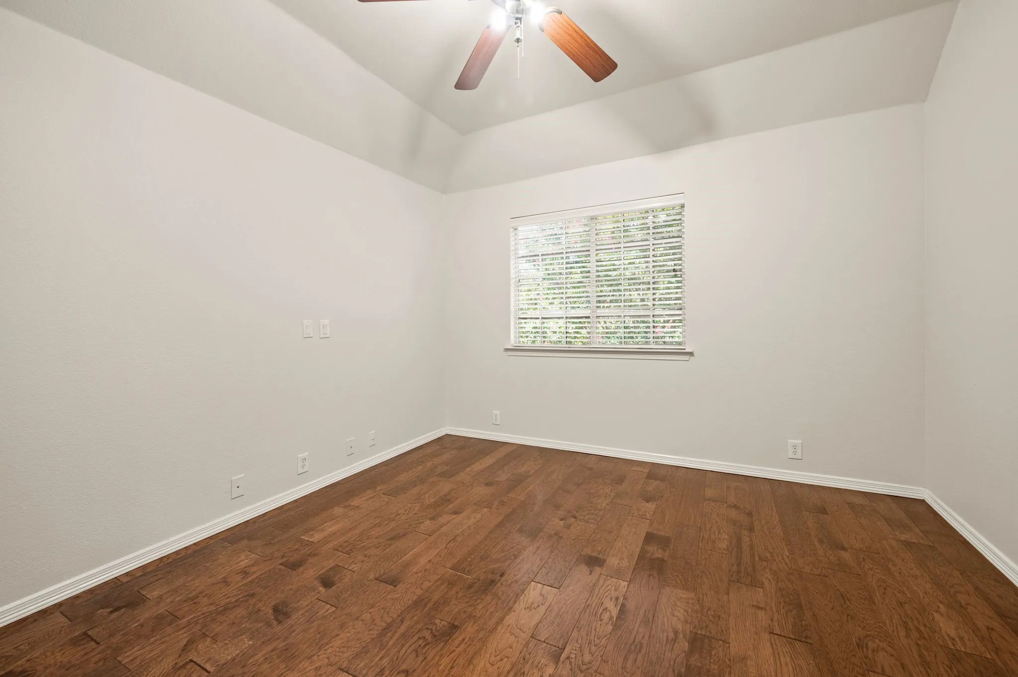 Vaulted ceiling with a ceiling fan, wood-finish flooring, and a window with blinds