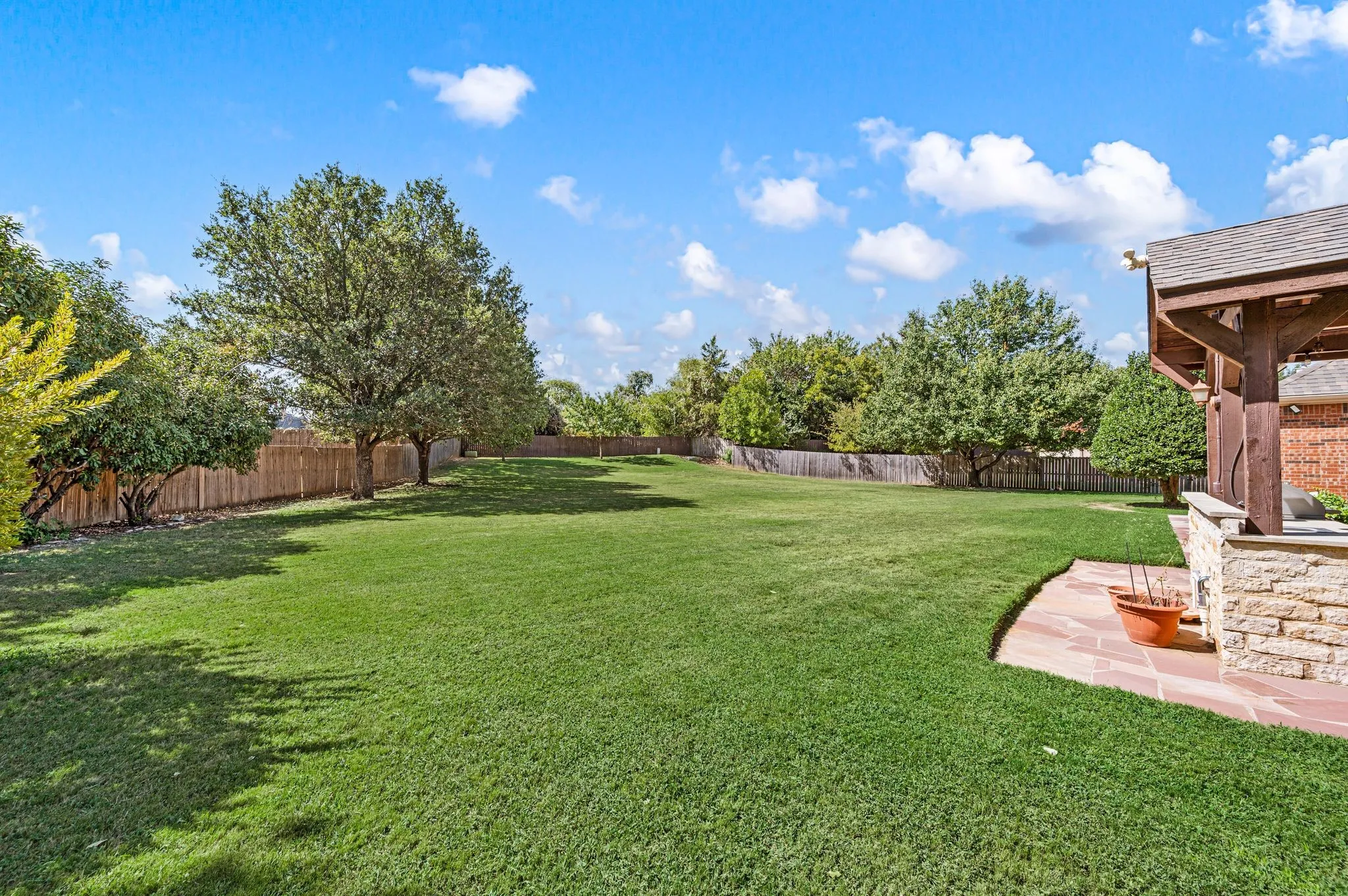 Spacious lawn area with mature trees and wood fencing