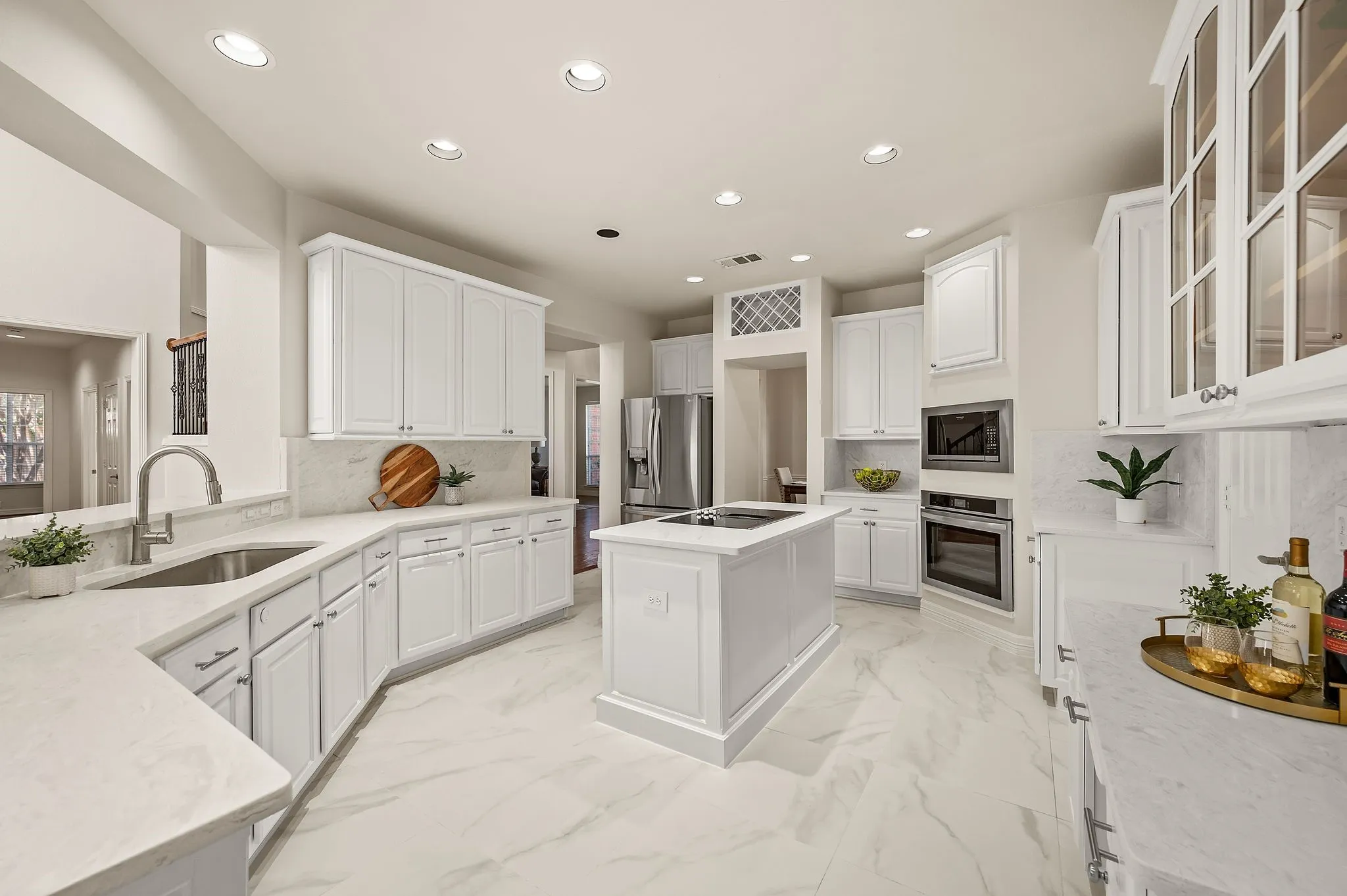 Kitchen featuring white cabinetry, light-toned countertops, a center island with cooktop, stainless steel built-in appliances, and recessed lighting