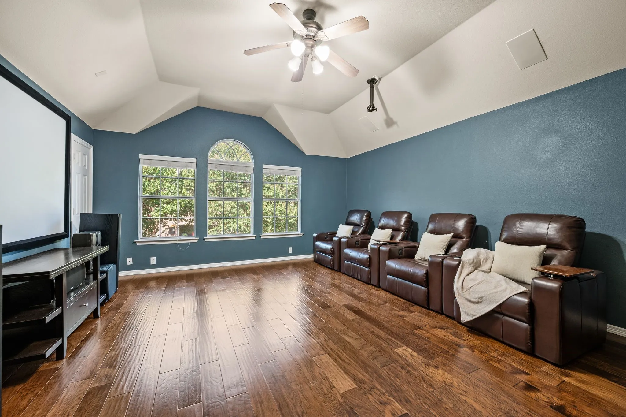 Vaulted ceiling with a ceiling fan, wood-finish flooring, recessed lighting, and multiple windows