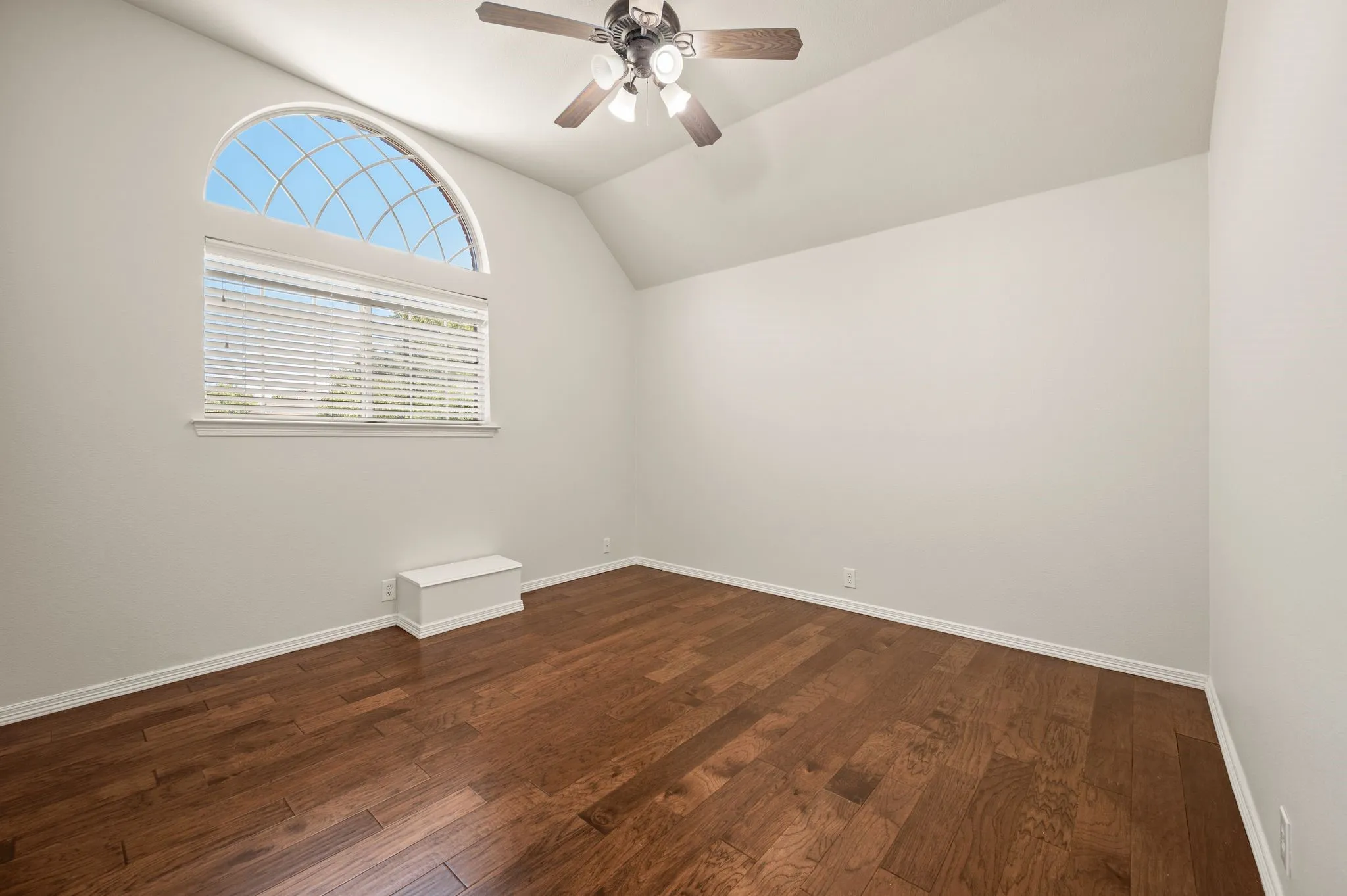 Vaulted ceiling with a ceiling fan, arched window, horizontal window blinds, and wood-finish flooring