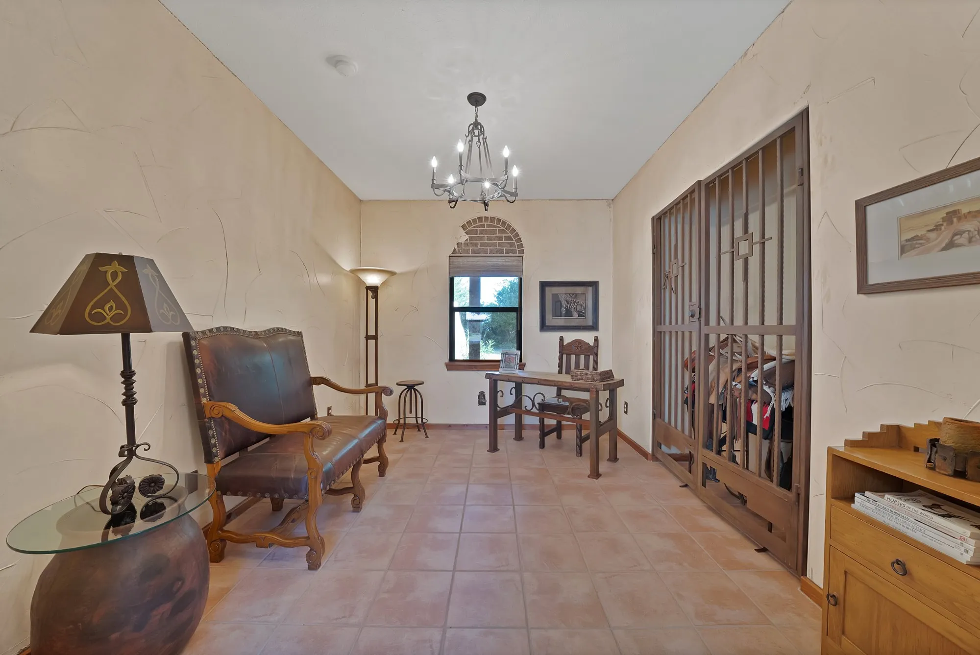 Study with a view of the backyard veranda, brick wall accent and southwest style iron doors.