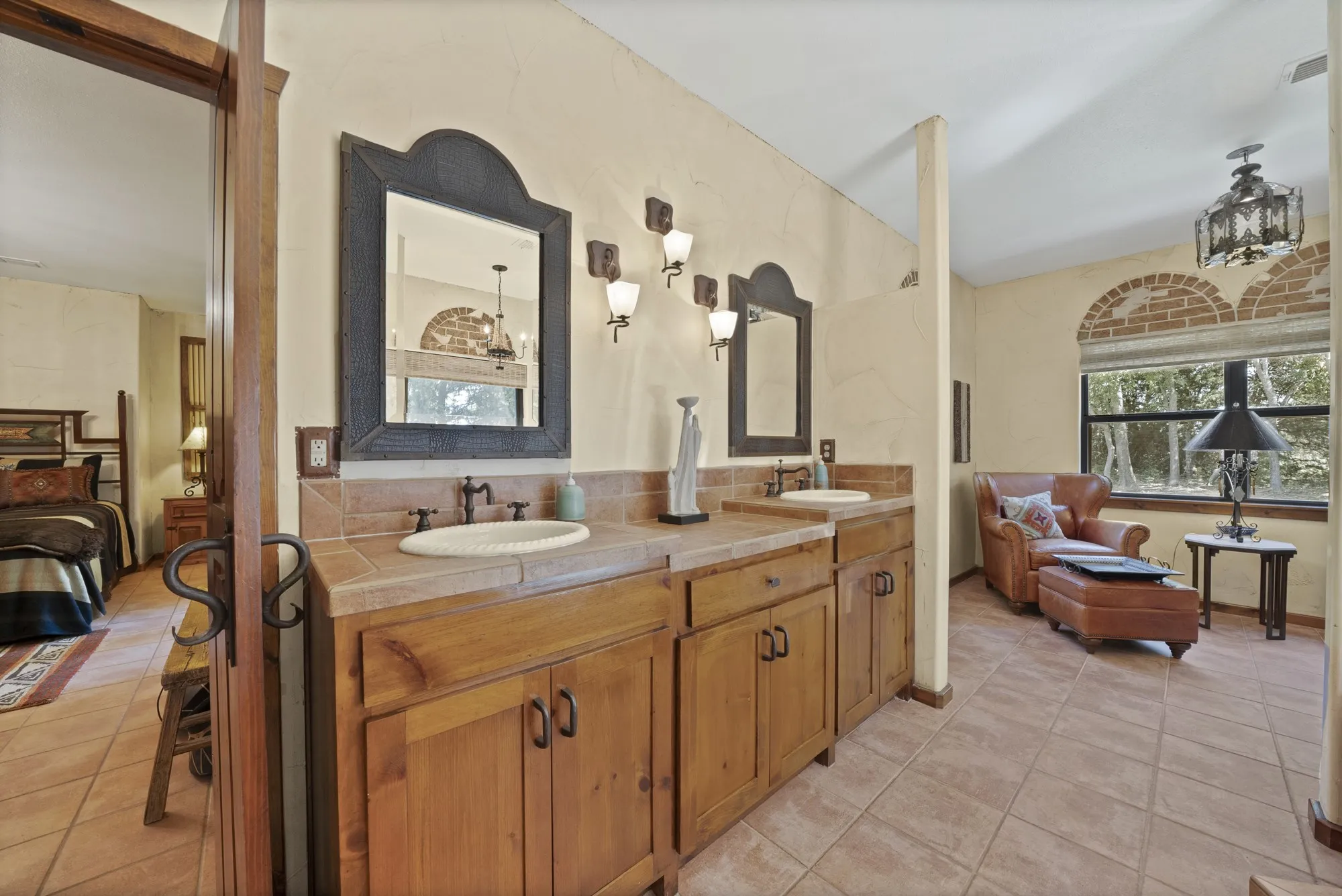 Primary bathroom with double sinks and view to sitting area and bedroom.