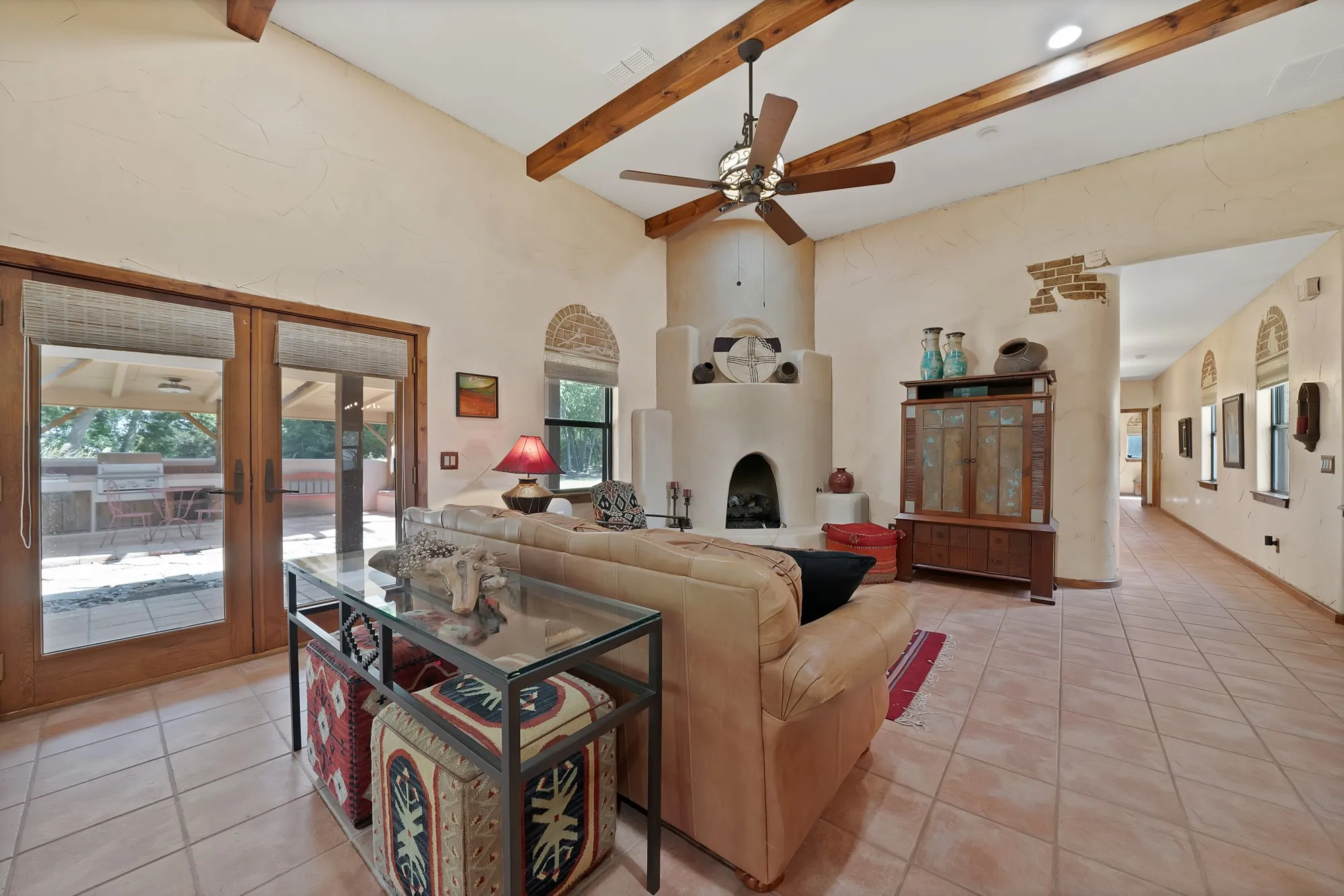 Family room with adobe style fireplace with gas logs looking towards the patio and hallway to the study and bedrooms.