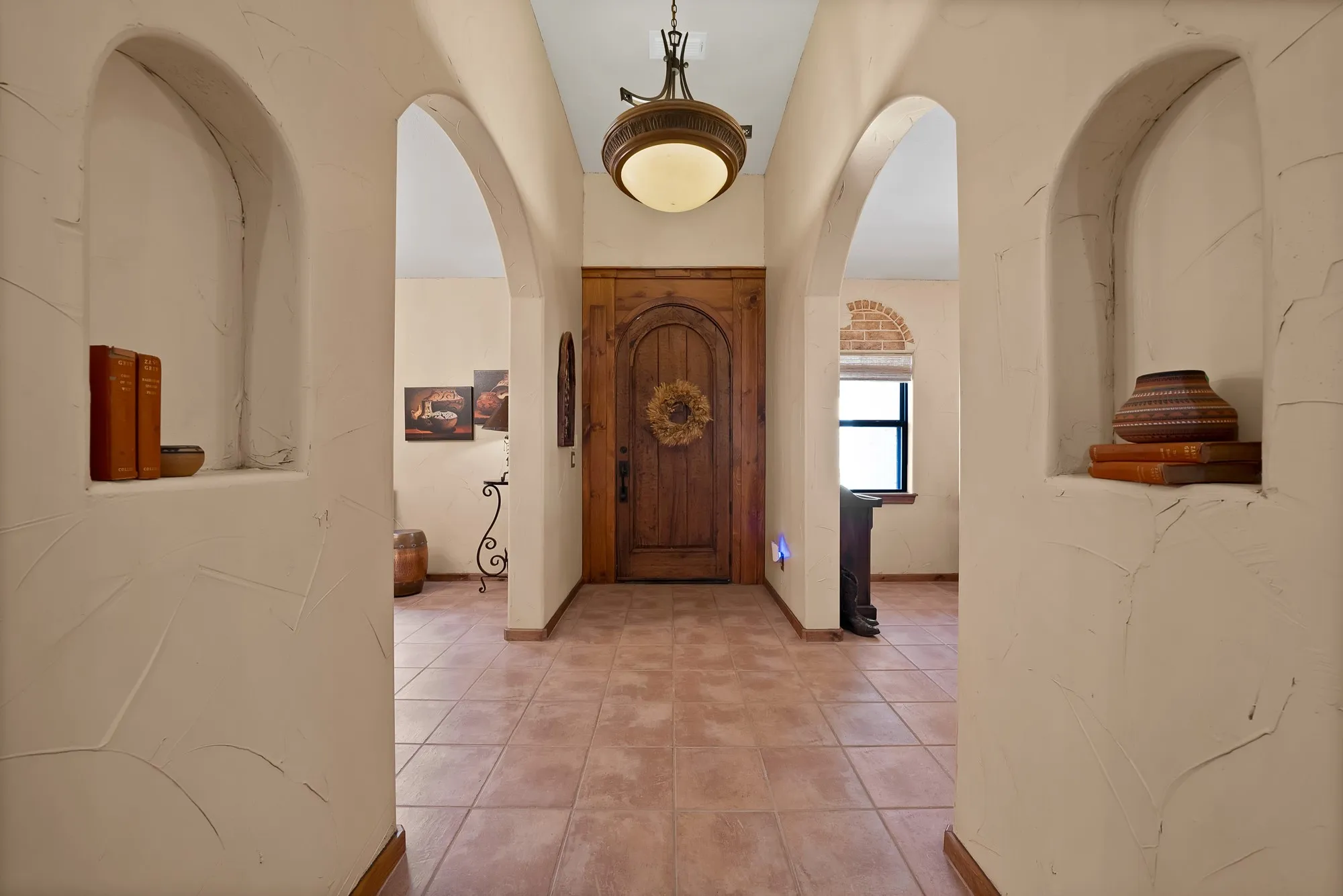Foyer front solid wood door with southwest style hardware arch and hardware. Art niches to showcase favorite pieces.