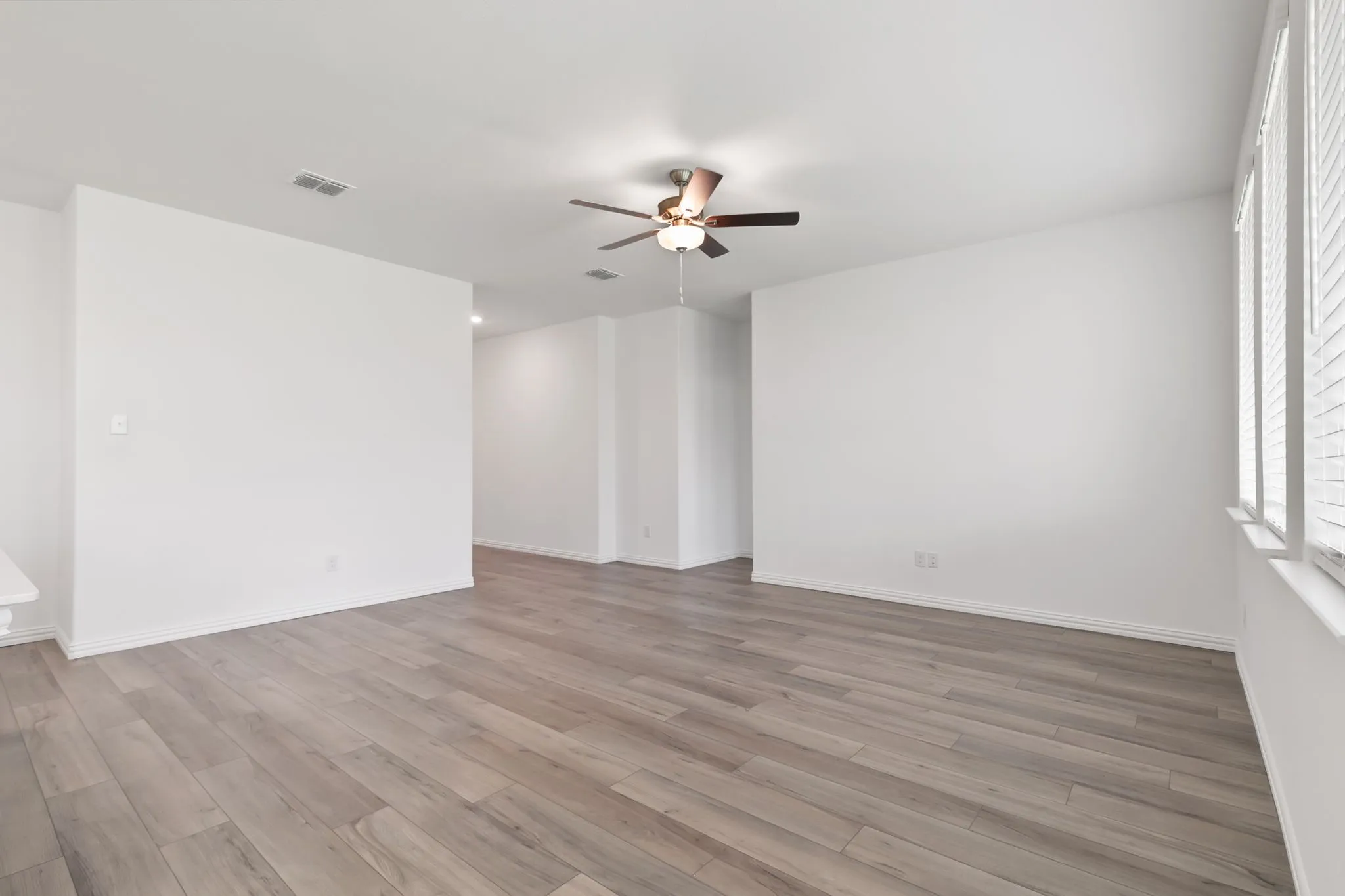 Empty room with ceiling fan and light hardwood / wood-style flooring