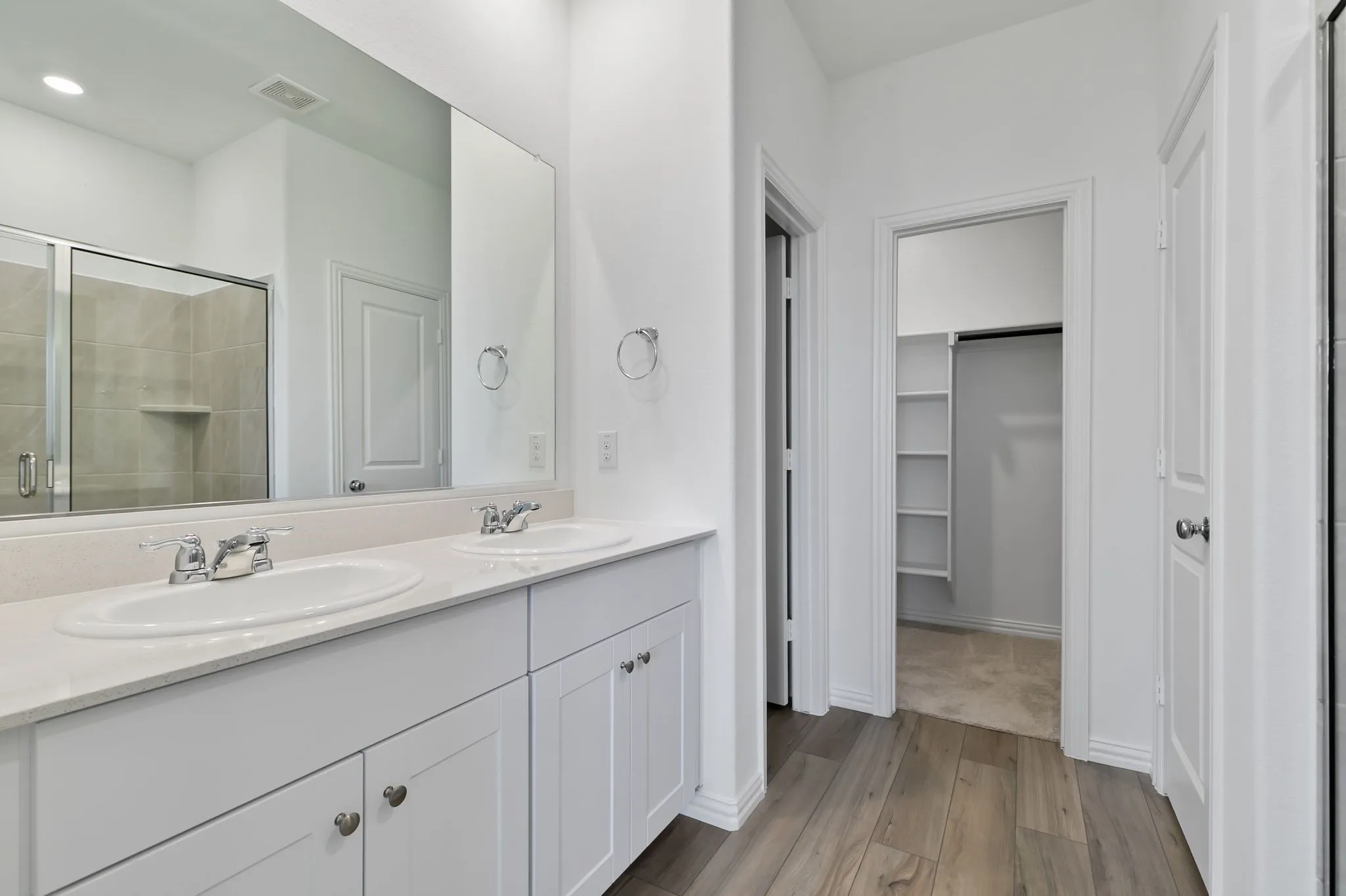 Bathroom with oversized vanity, an enclosed shower, hardwood / wood-style flooring, and dual sinks