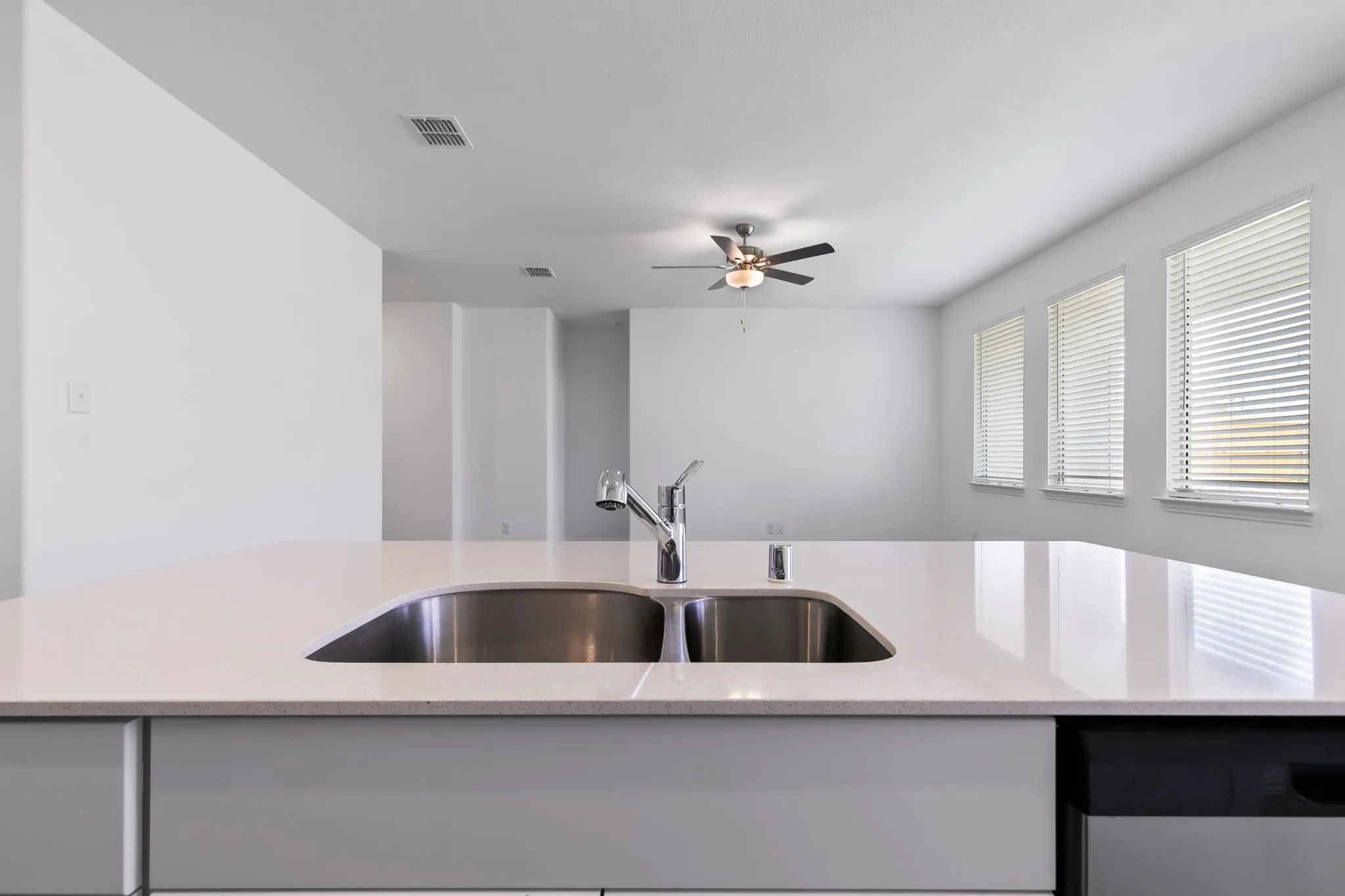 Kitchen with sink, ceiling fan, dishwasher, and light stone counters