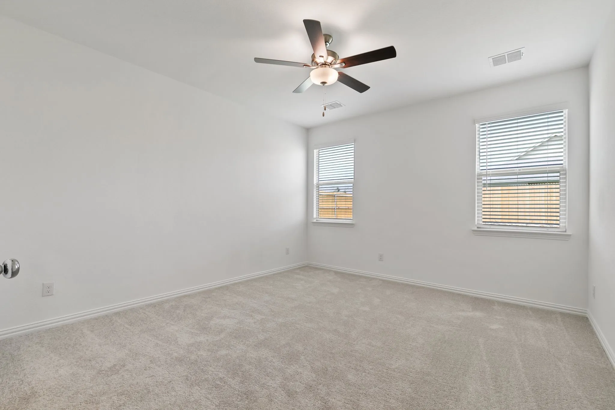 Empty room with light colored carpet and ceiling fan
