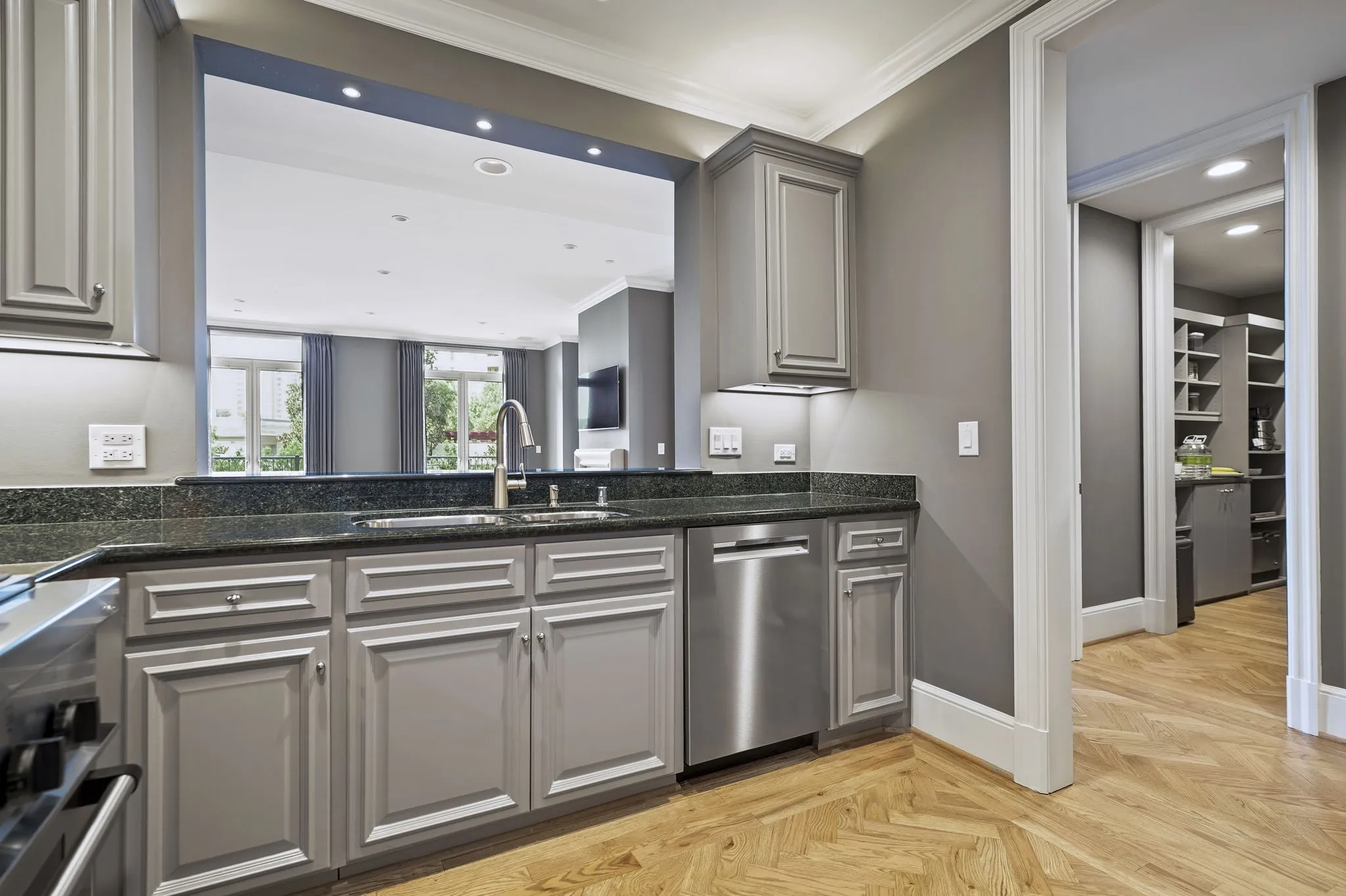 Sophisticated kitchen features custom cabinetry, stainless steel top of the line kitchen appliances and beautiful solid oak flooring with intricate herringbone pattern.