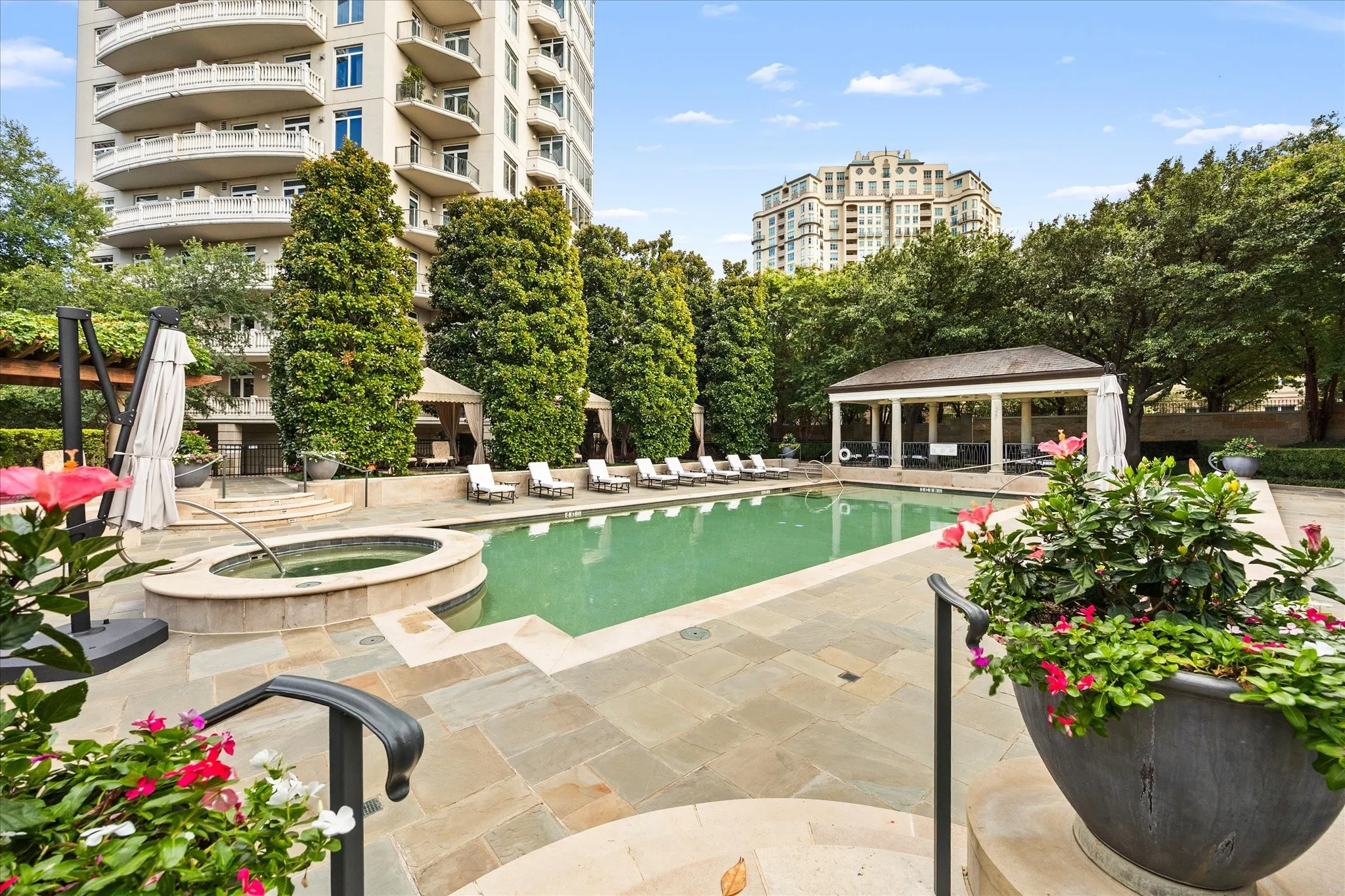 Expansive outdoor area featuring a swimming pool, spa, stone patio, and a covered pavilion