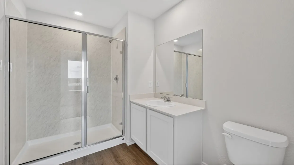 Walk-in shower with clear glass enclosure and light-toned wall surround