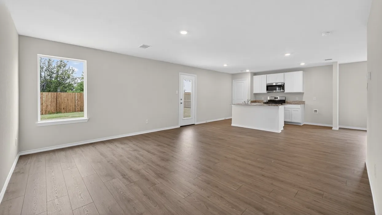 Open-concept living space featuring wood-finish flooring, recessed lighting, and a kitchen with white cabinetry, stainless steel appliances, and a breakfast bar with a stone-finish countertop