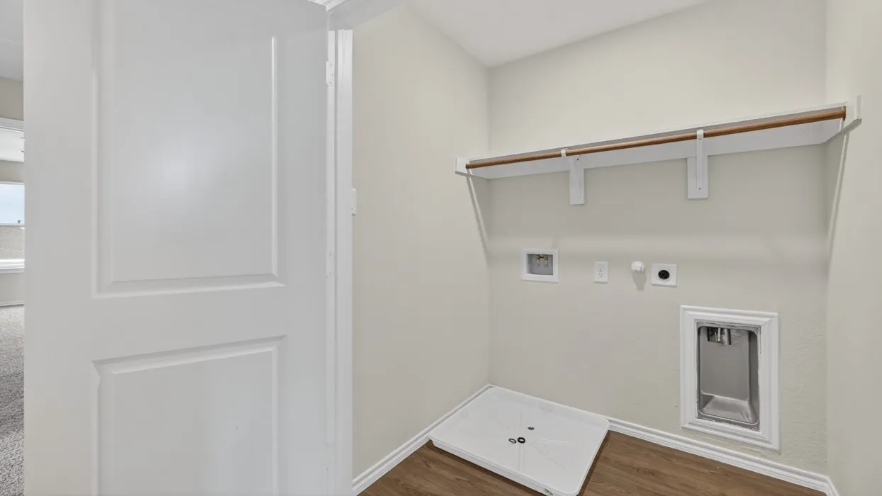 Utility area featuring wood-finish flooring, a white interior door, a built-in shelf, and a clothing rod