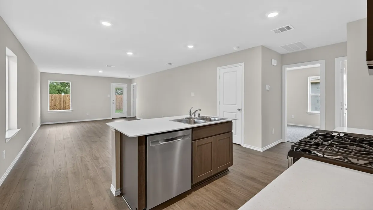 Open-concept living space featuring wood-finish flooring, recessed lighting, and an island with an integrated stainless steel sink and dishwasher