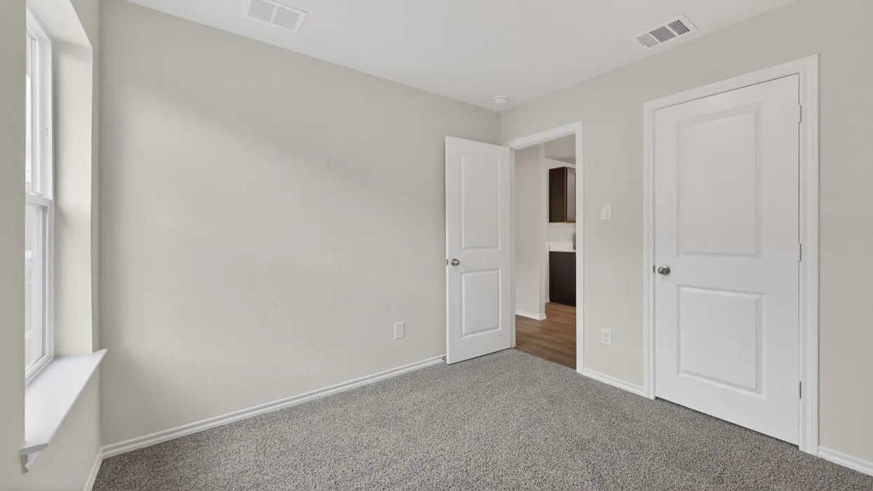 Light gray walls, window with white trim, gray carpet, and white two-panel doors