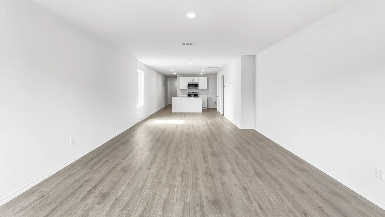 Open-concept living space featuring wood-finish flooring, recessed lighting, white walls, and a visible kitchen with white cabinetry and appliances