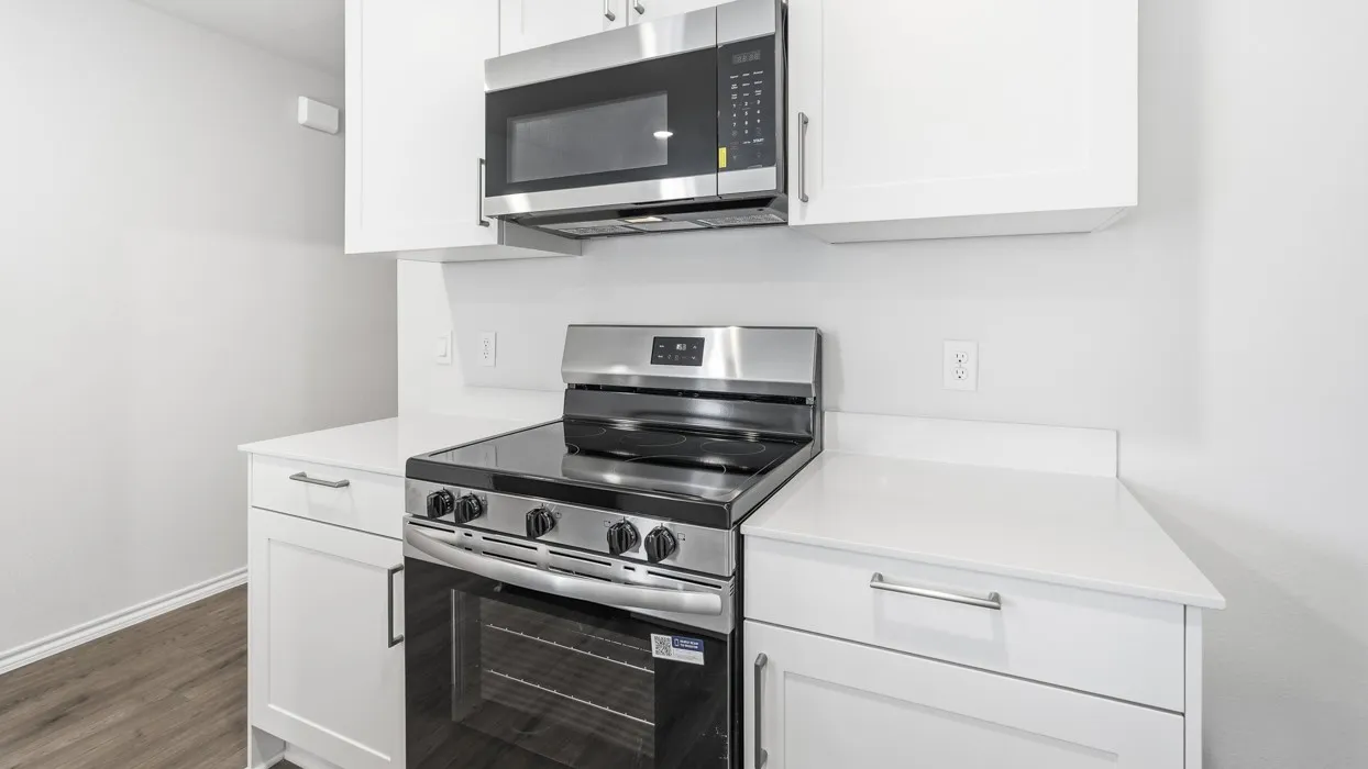 White cabinetry with chrome hardware, white countertops, stainless steel electric range, and stainless steel microwave