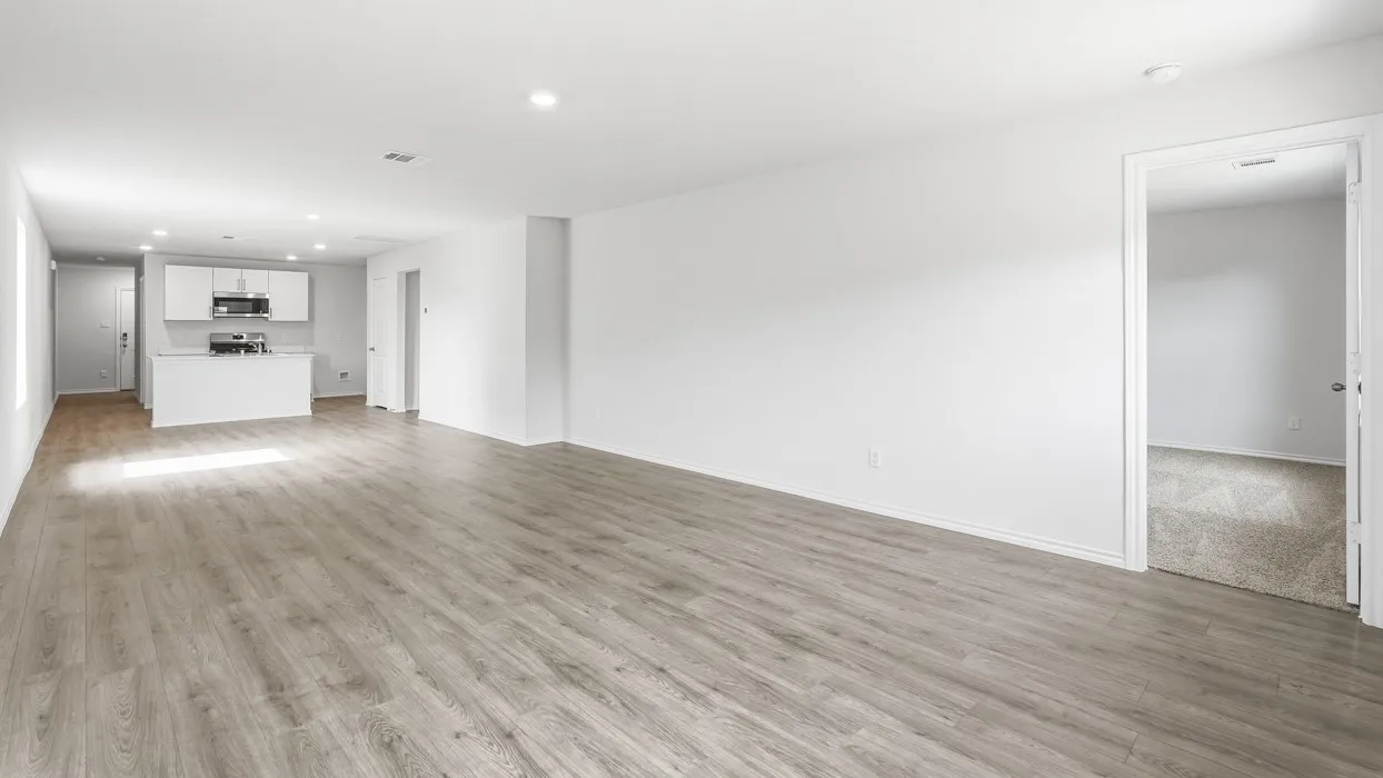 Open-concept living area featuring wood-finish flooring, recessed lighting, and a kitchen with white cabinetry and stainless steel appliances