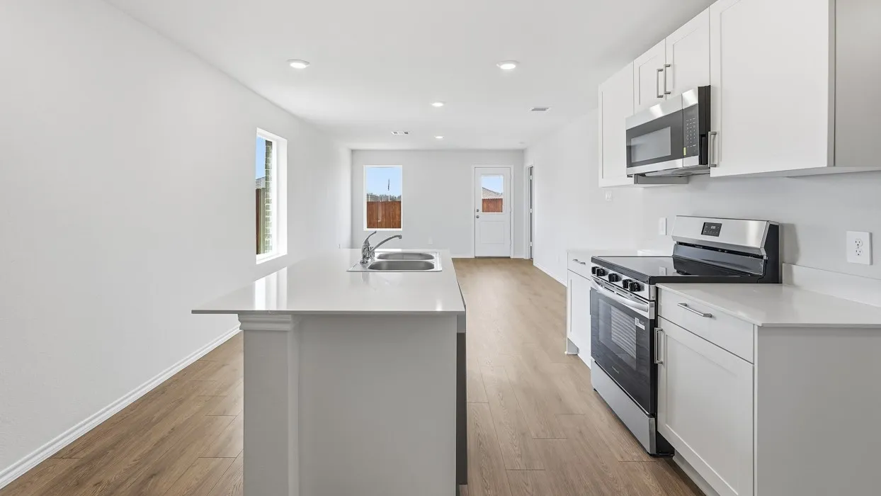 Kitchen featuring an island with a stainless steel sink, white cabinetry, stainless steel appliances, and wood-finish flooring