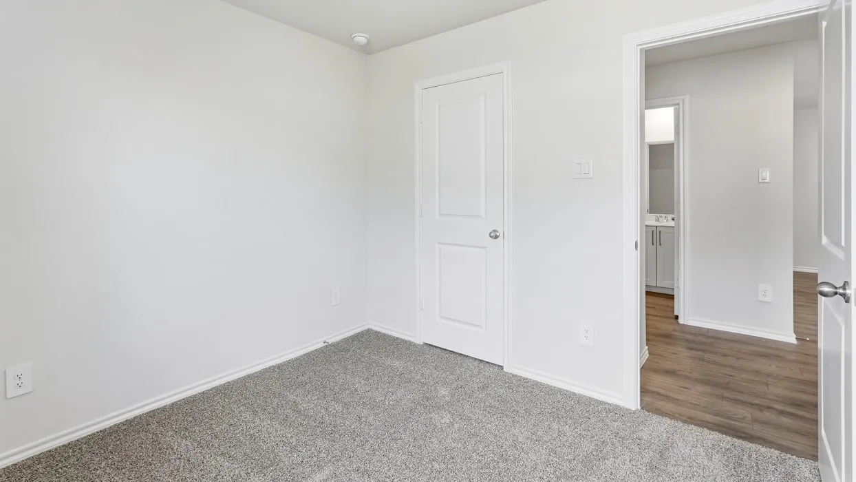 Neutral tone walls, grey carpet flooring, white trim, recessed lighting, and a white interior door