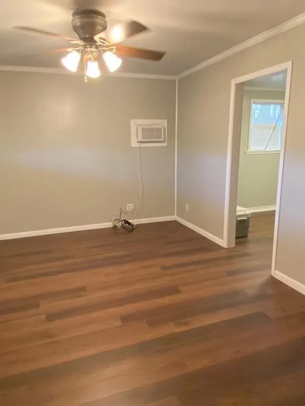 Wood-finish plank flooring throughout, ceiling fan with integrated lighting, and a wall-mounted air conditioning unit