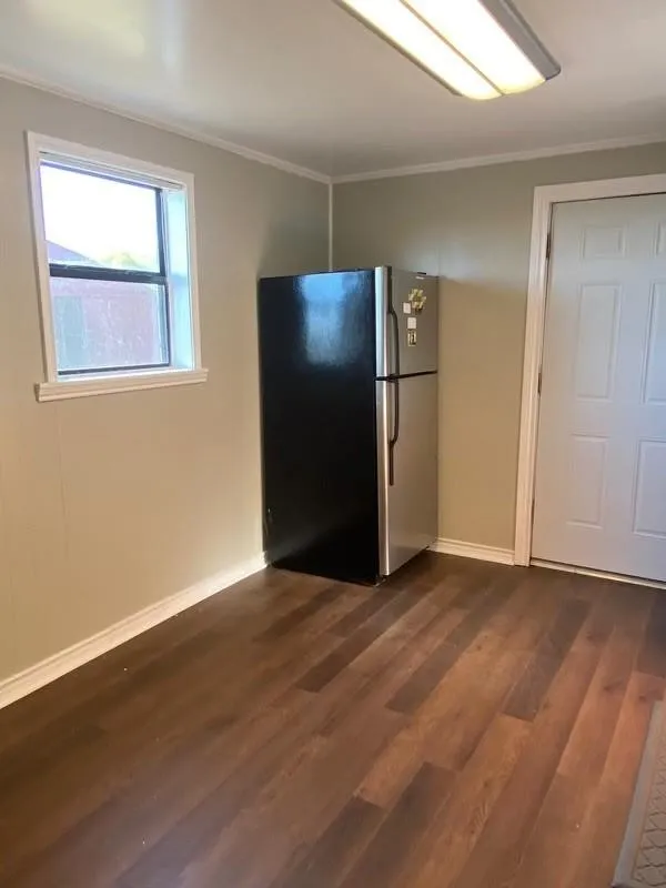 Wood-finish flooring, white trim, and a white paneled door