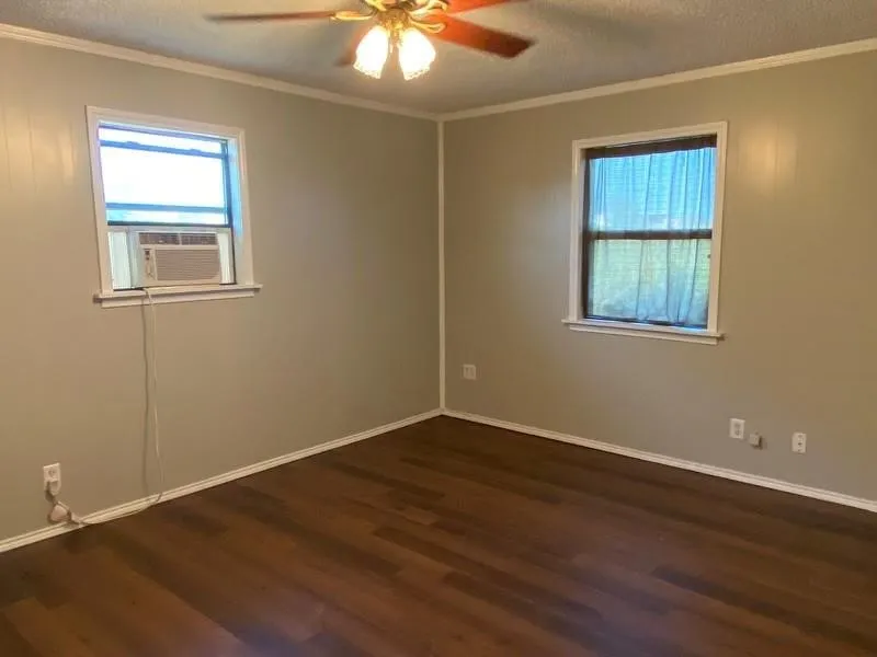 Wood-finish flooring with light-toned wall panels, white trim, and a ceiling fan