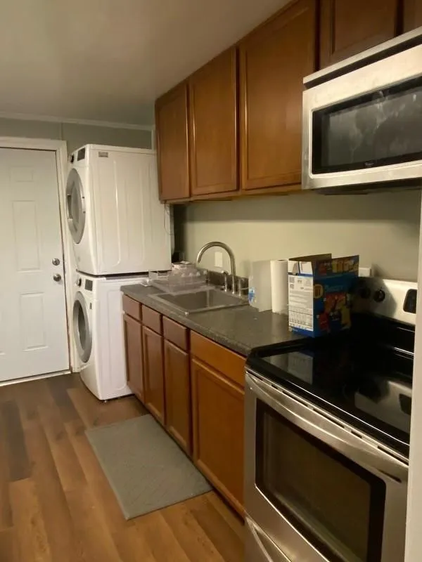 Kitchenette featuring wood-finish flooring, wood cabinetry, a stainless steel sink, and a stainless steel oven