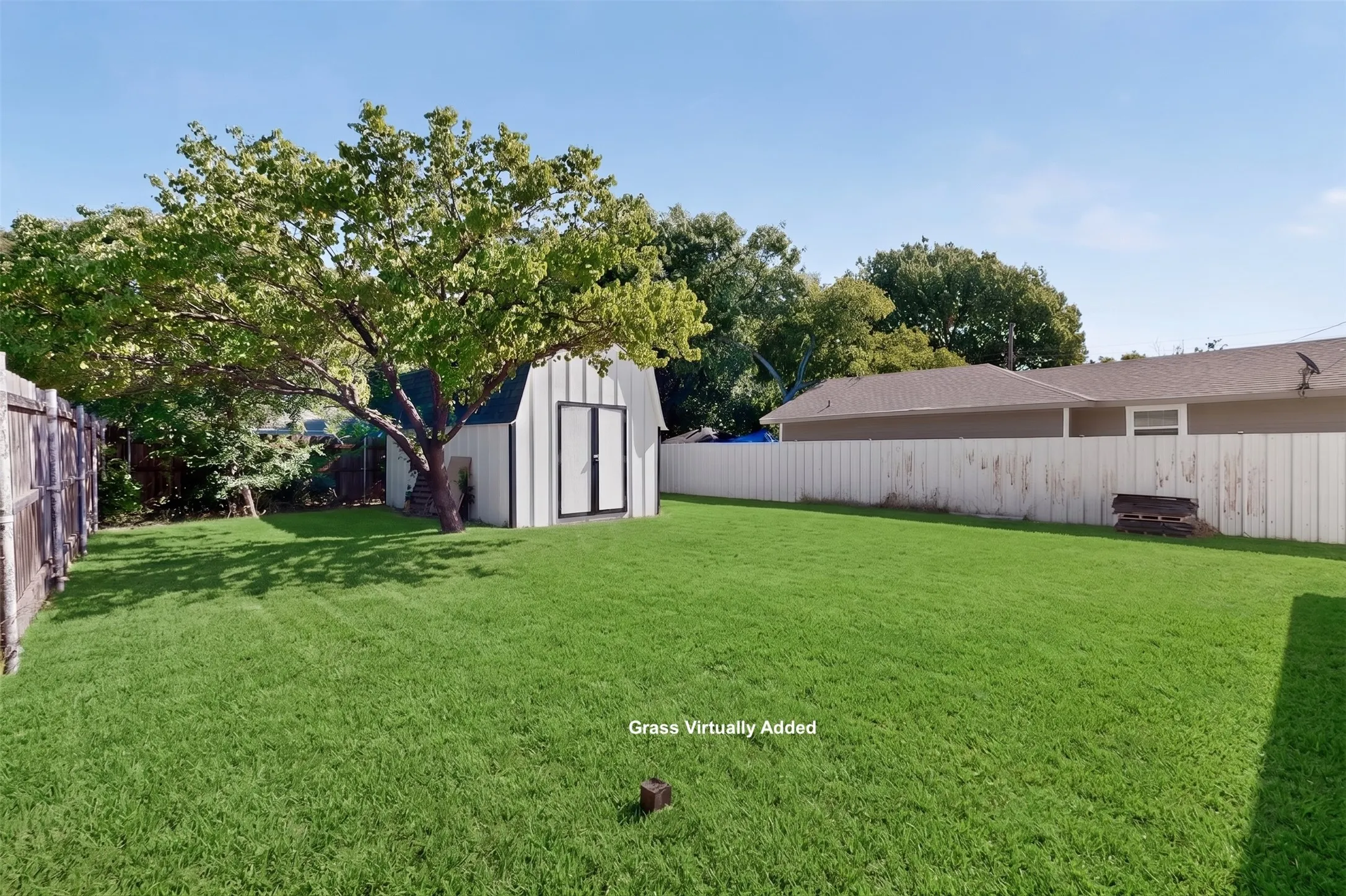 Expansive fenced backyard featuring a storage shed with double doors and a mature tree