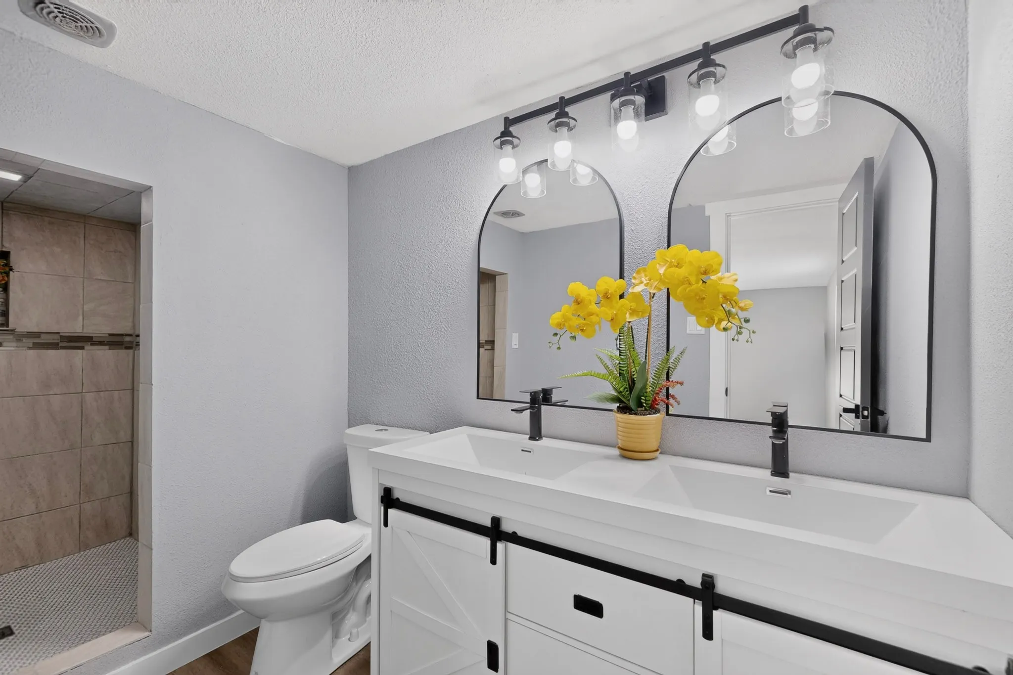Dual vanity with matte black fixtures, arched mirrors, and a white countertop
