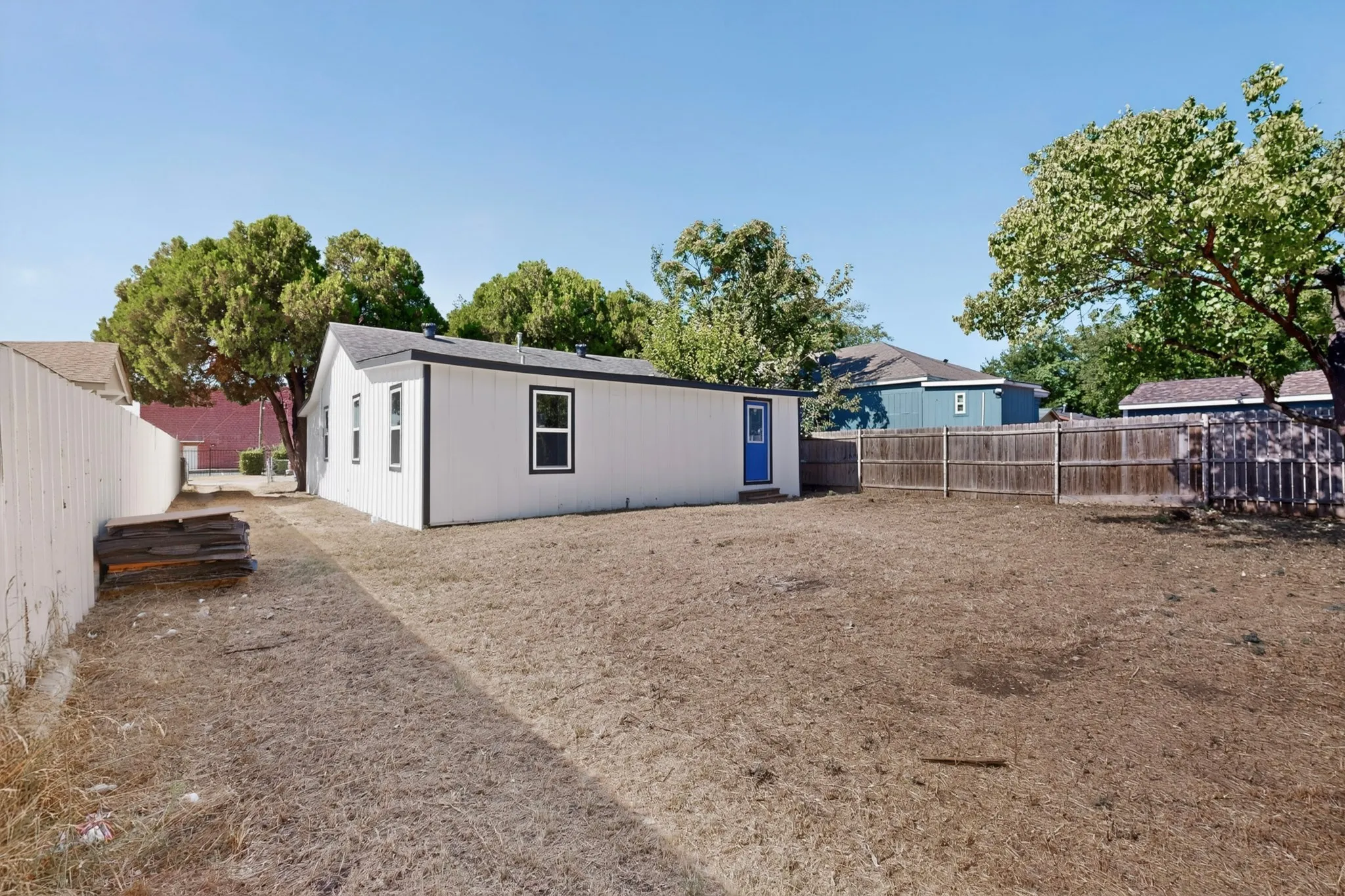 Expansive rear yard with a wood fence perimeter and a white-sided structure
