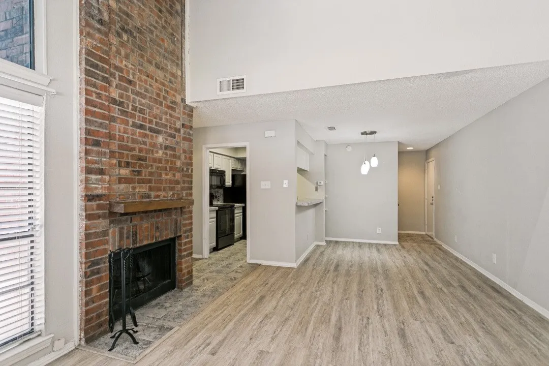 Brick fireplace with a wood-finish mantel and hearth, wood-finish flooring, and white walls
