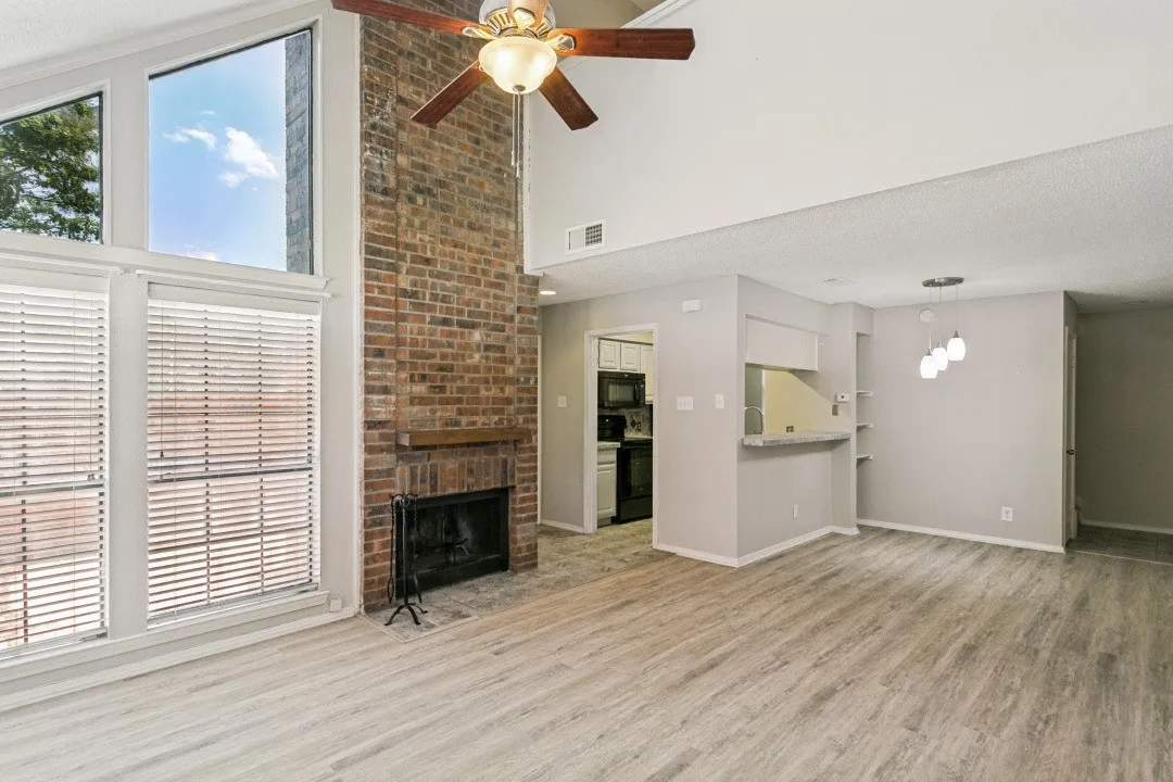 Vaulted ceilings, wood-finish flooring, and a brick-faced fireplace with a wood mantel