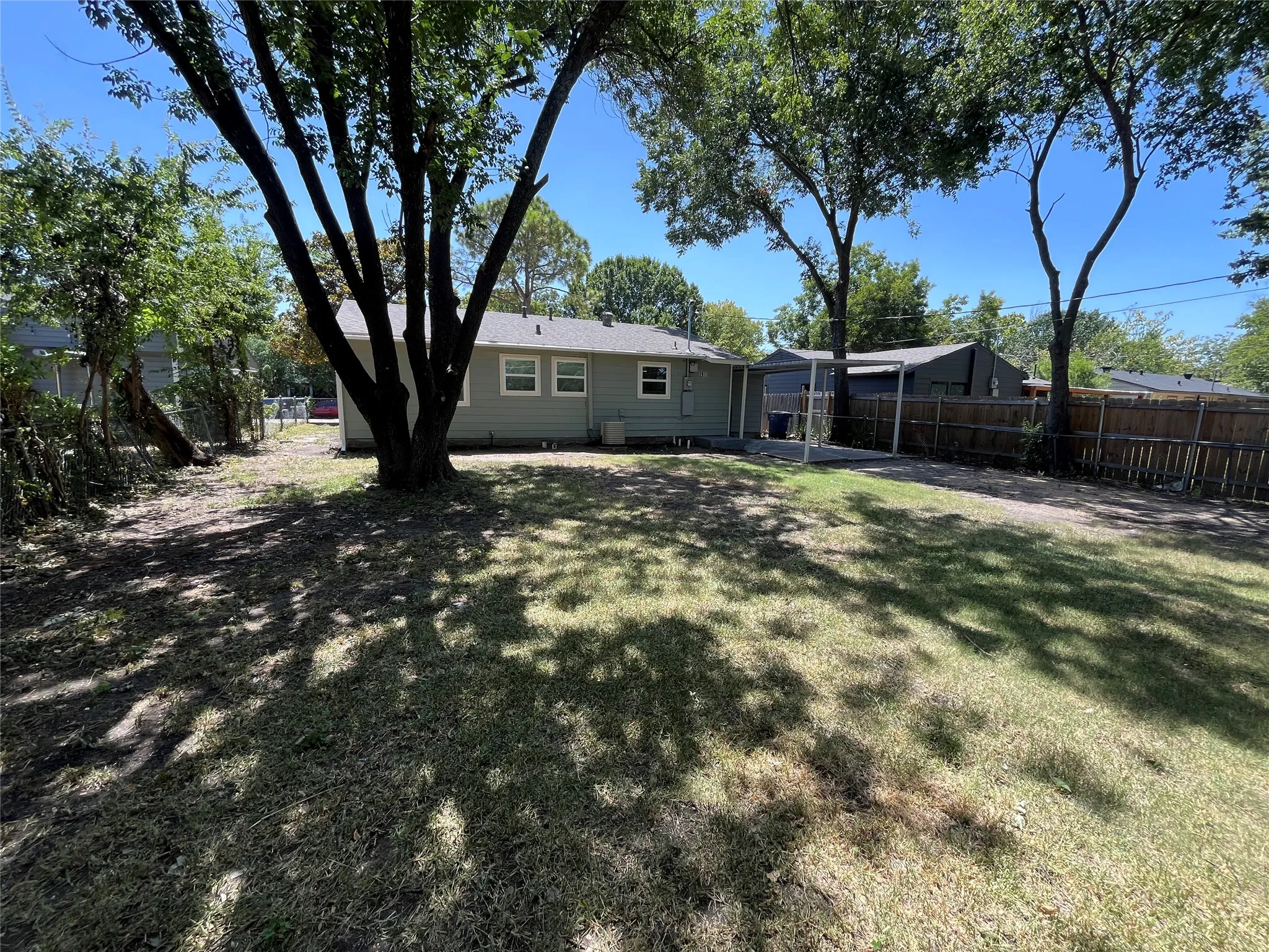 Expansive backyard featuring mature trees, a wood privacy fence, and a concrete patio
