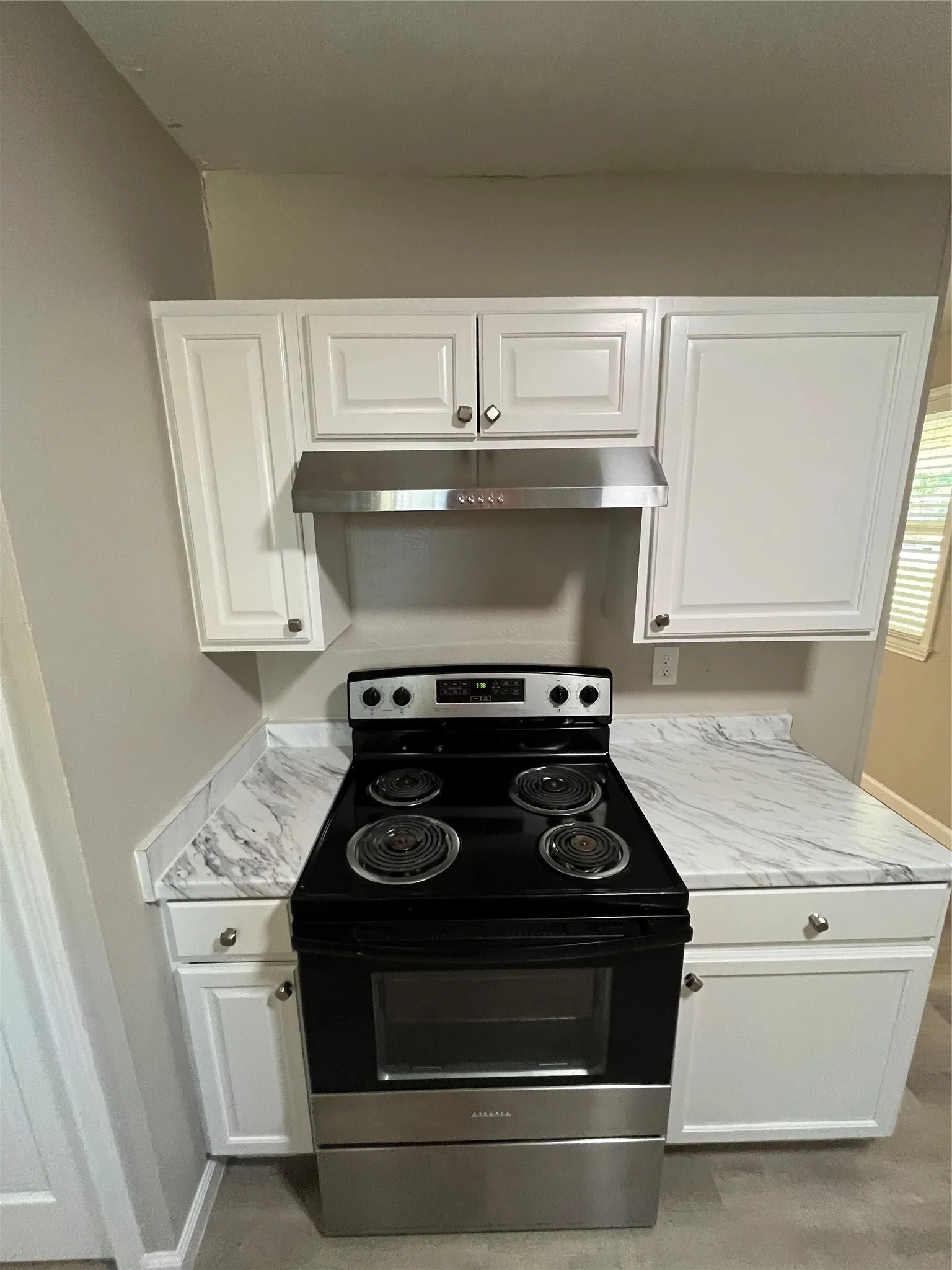 White shaker-style cabinetry with chrome hardware, stainless steel range hood, and black electric range