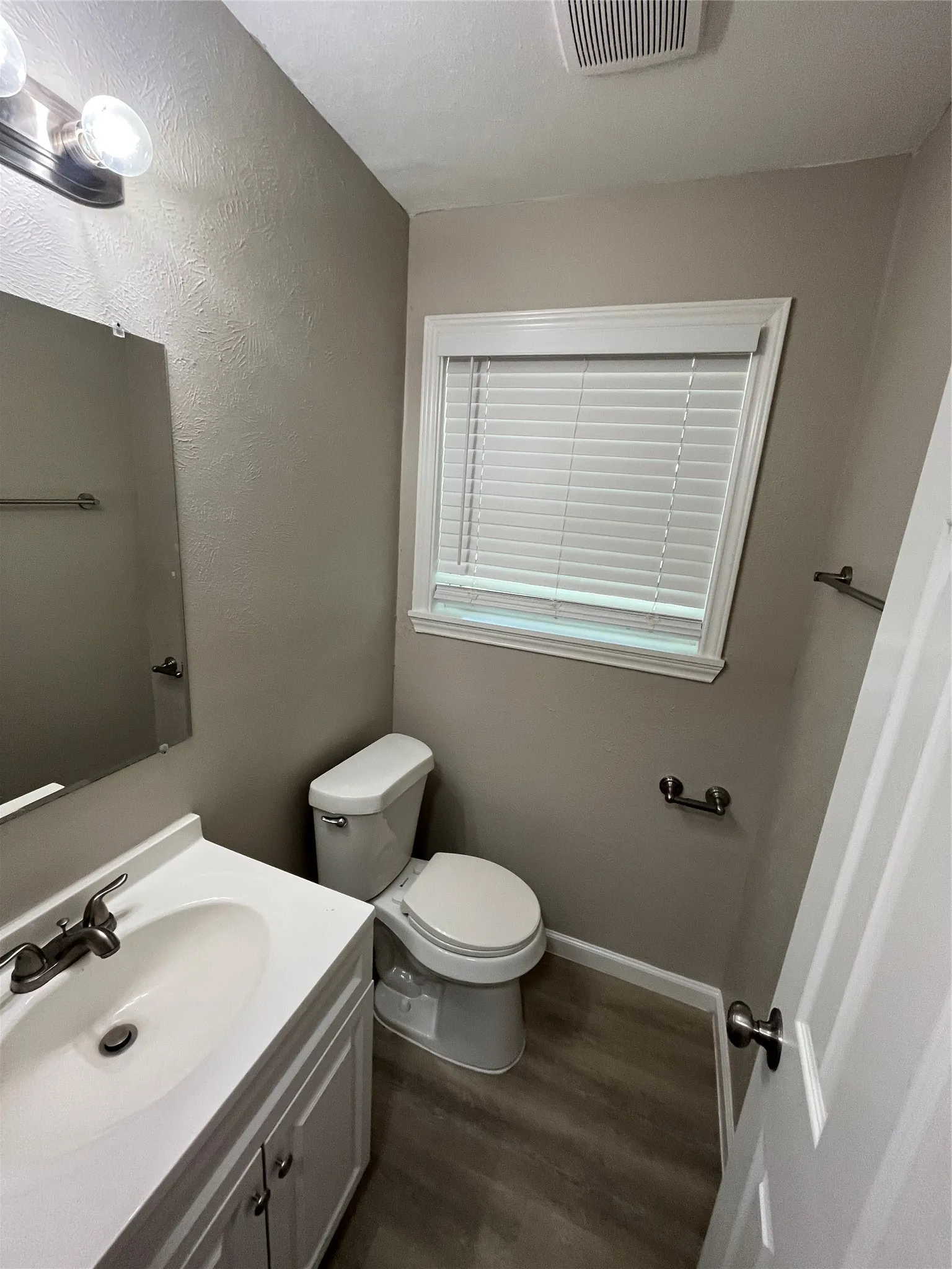 White vanity with an integrated sink, brushed nickel faucet, and wood-finish flooring