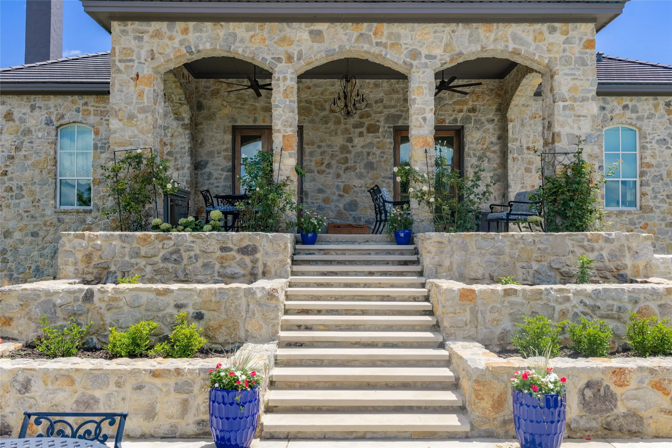 Stone exterior with arched entryways, tiered stone retaining walls, and a multi-level concrete staircase