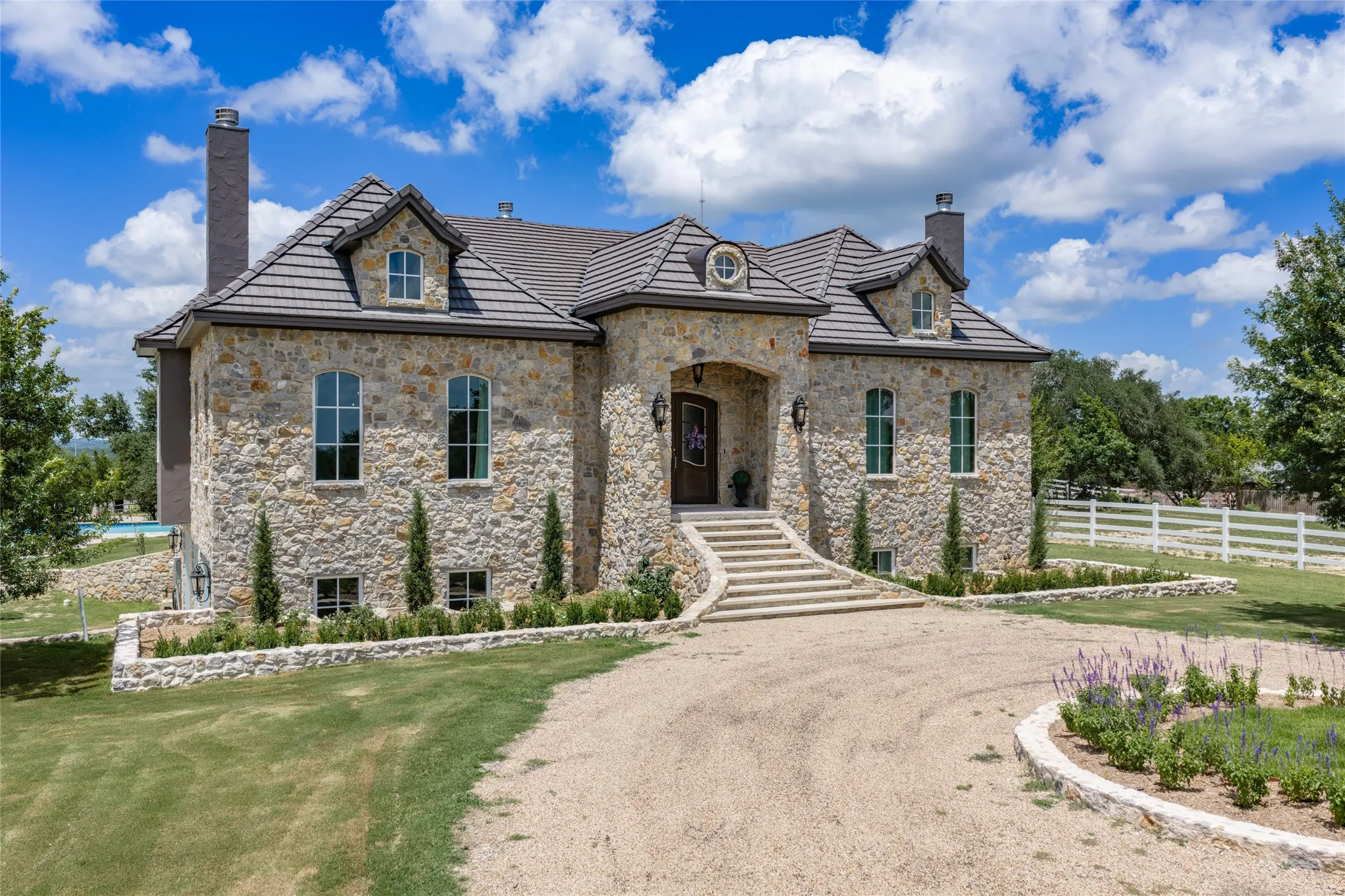 Stone exterior with multiple chimneys, arched windows, and a tiled roof