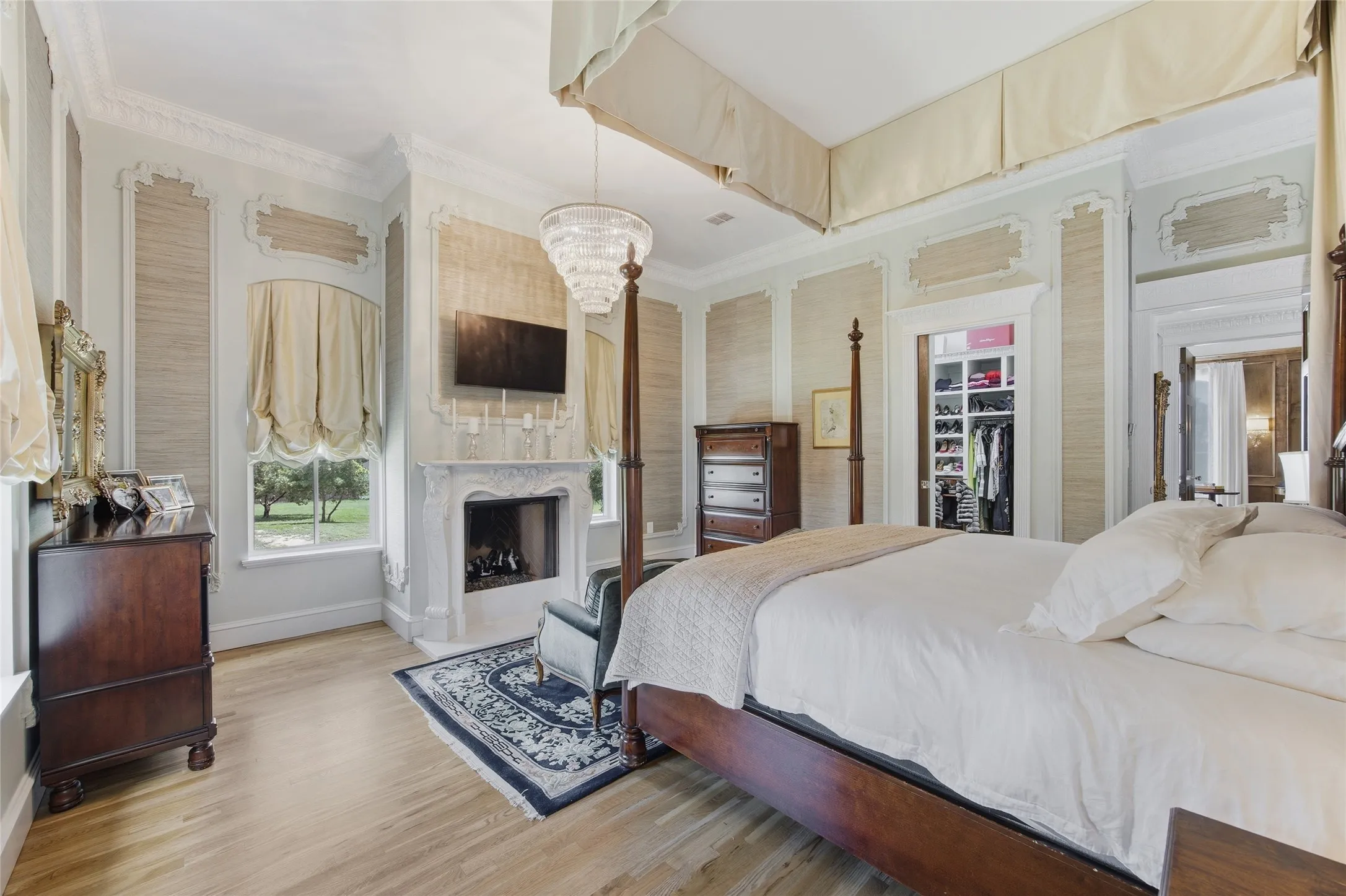 Hardwood flooring, ornate fireplace with mantel, built-in shelving in closet, crown molding, and a chandelier