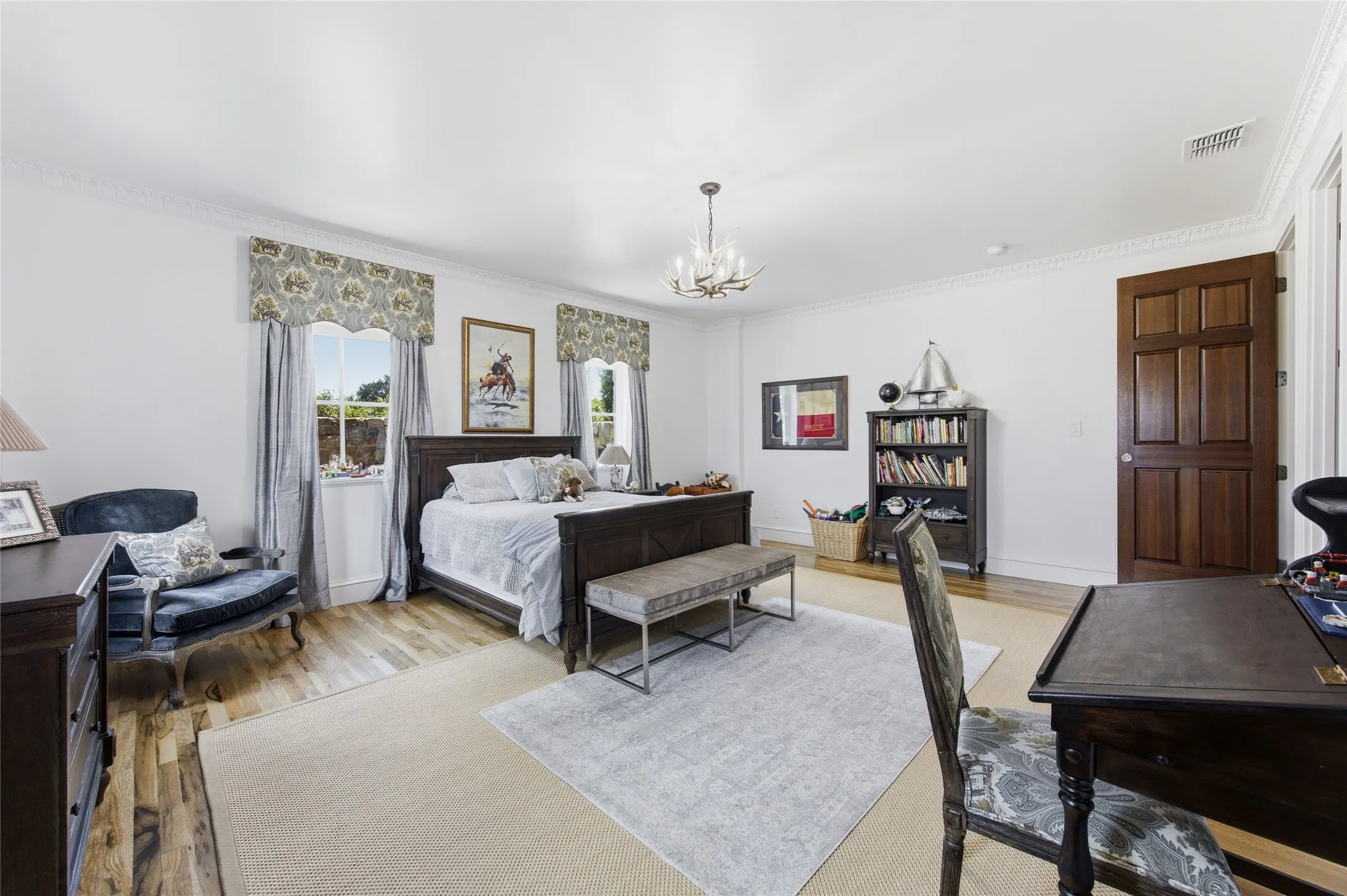 Wood-finish flooring, white walls with crown molding, and two windows with drapery