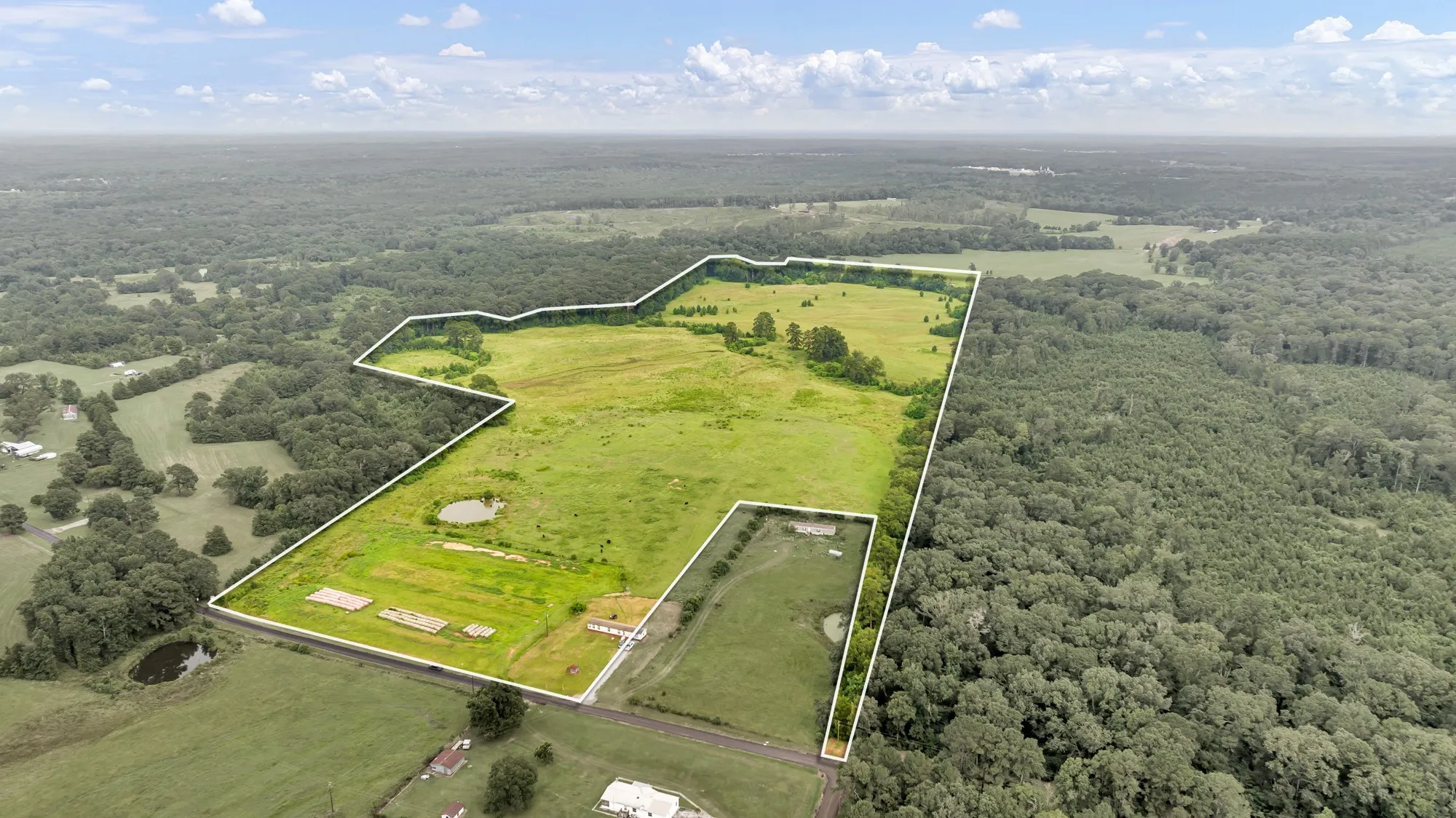 Expansive land parcel featuring open fields, wooded sections, and multiple ponds