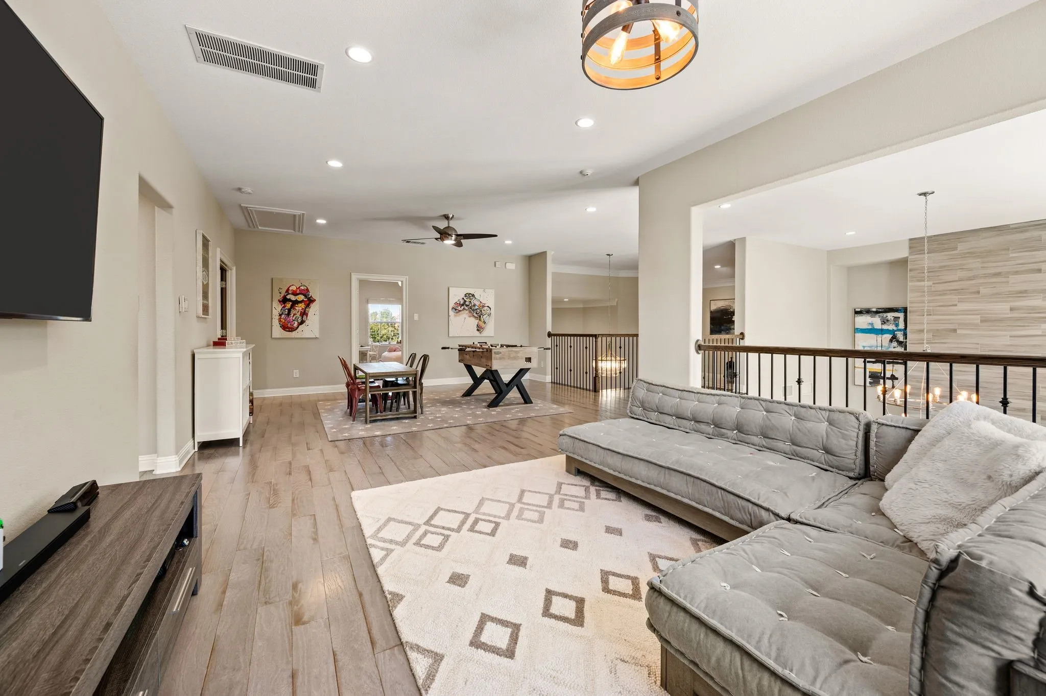 Wood-finish flooring, recessed lighting, ceiling fan, and open railing