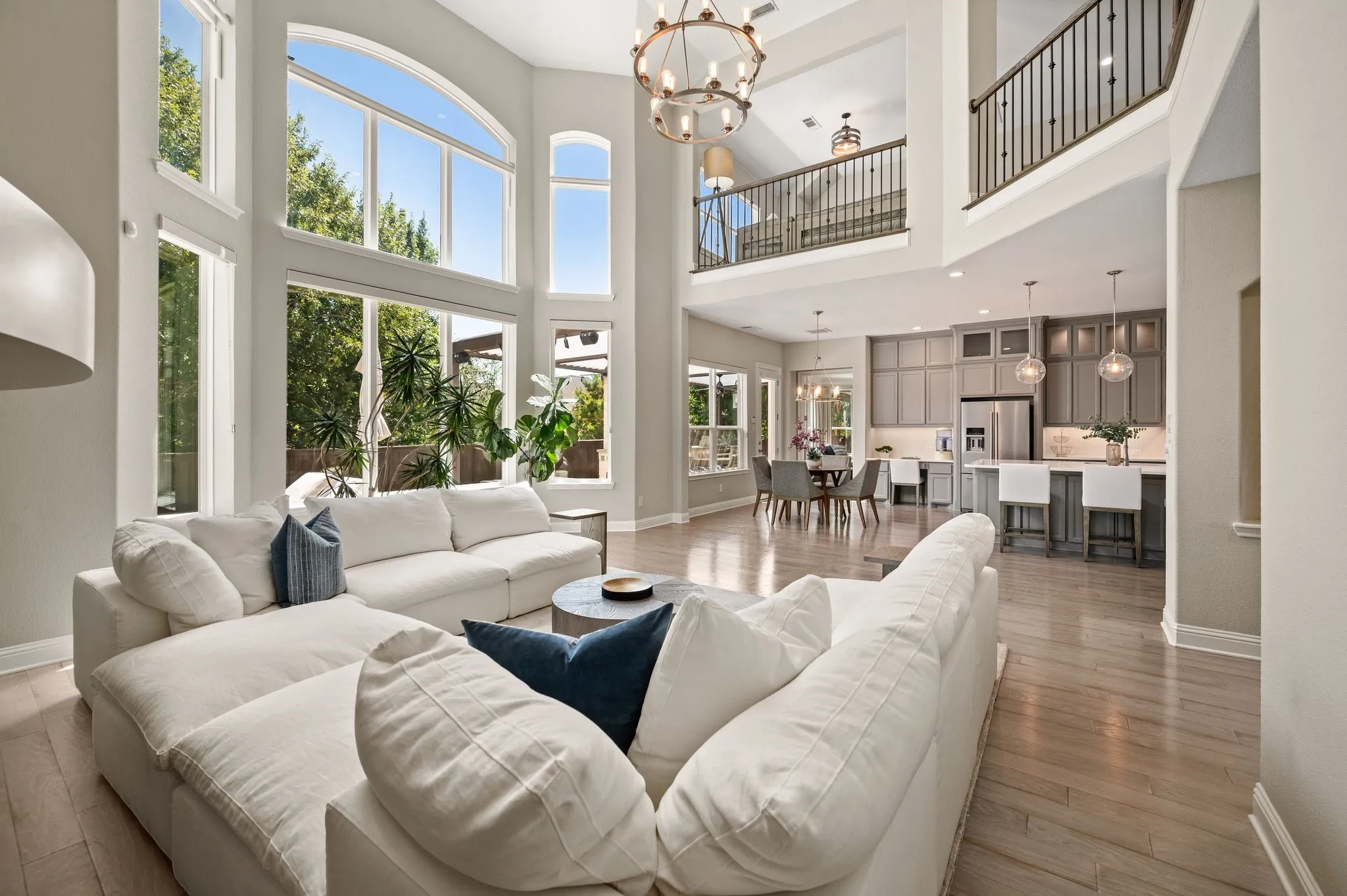 Soaring two-story great room with floor-to-ceiling arched windows, hardwood flooring, and a pendant light fixture