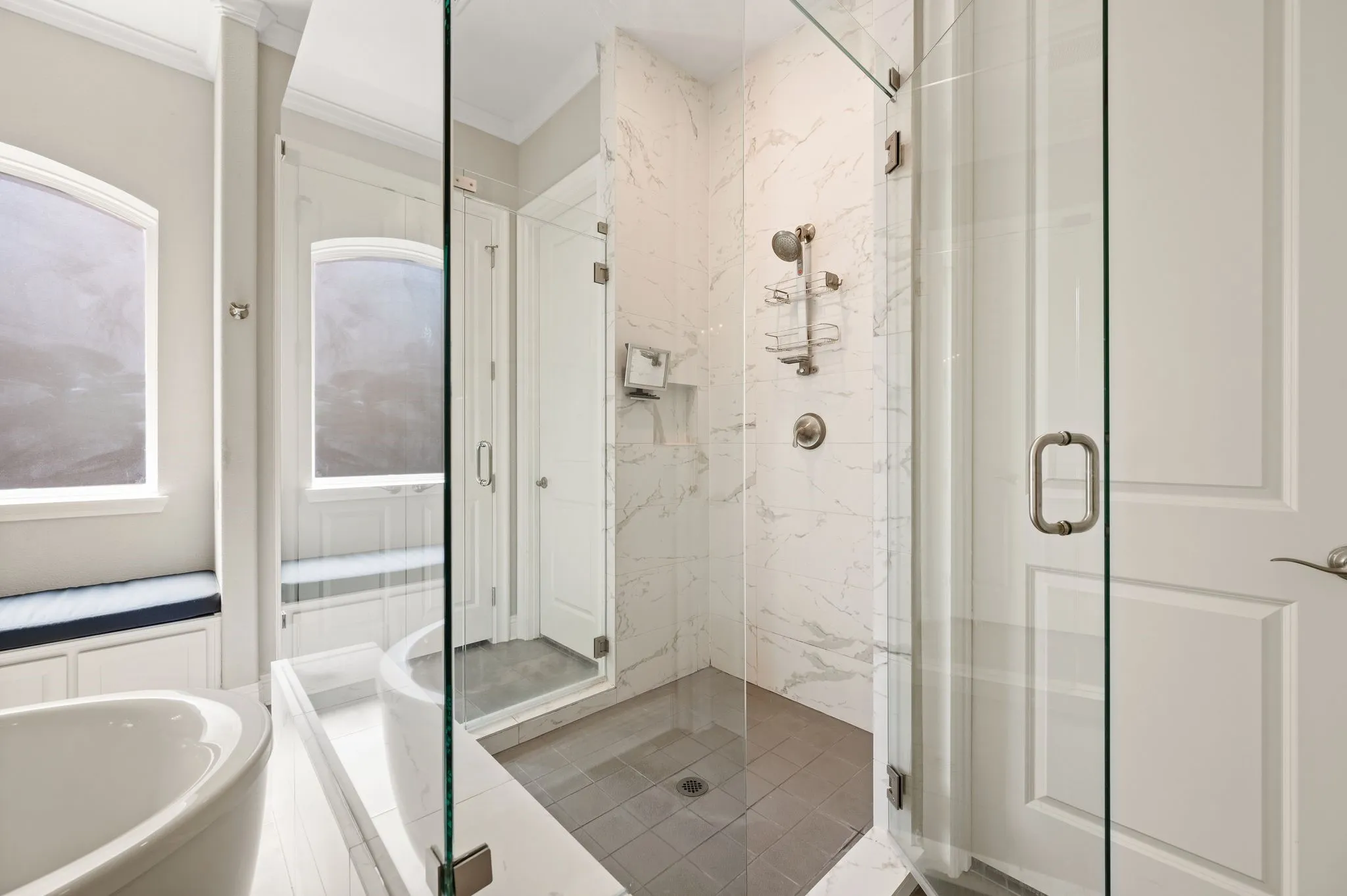 Spa-inspired primary bathroom featuring a frameless glass-enclosed walk-in shower with subway tile surround, dual showerheads, a freestanding soaking tub, polished nickel fixtures, and tile flooring throughout