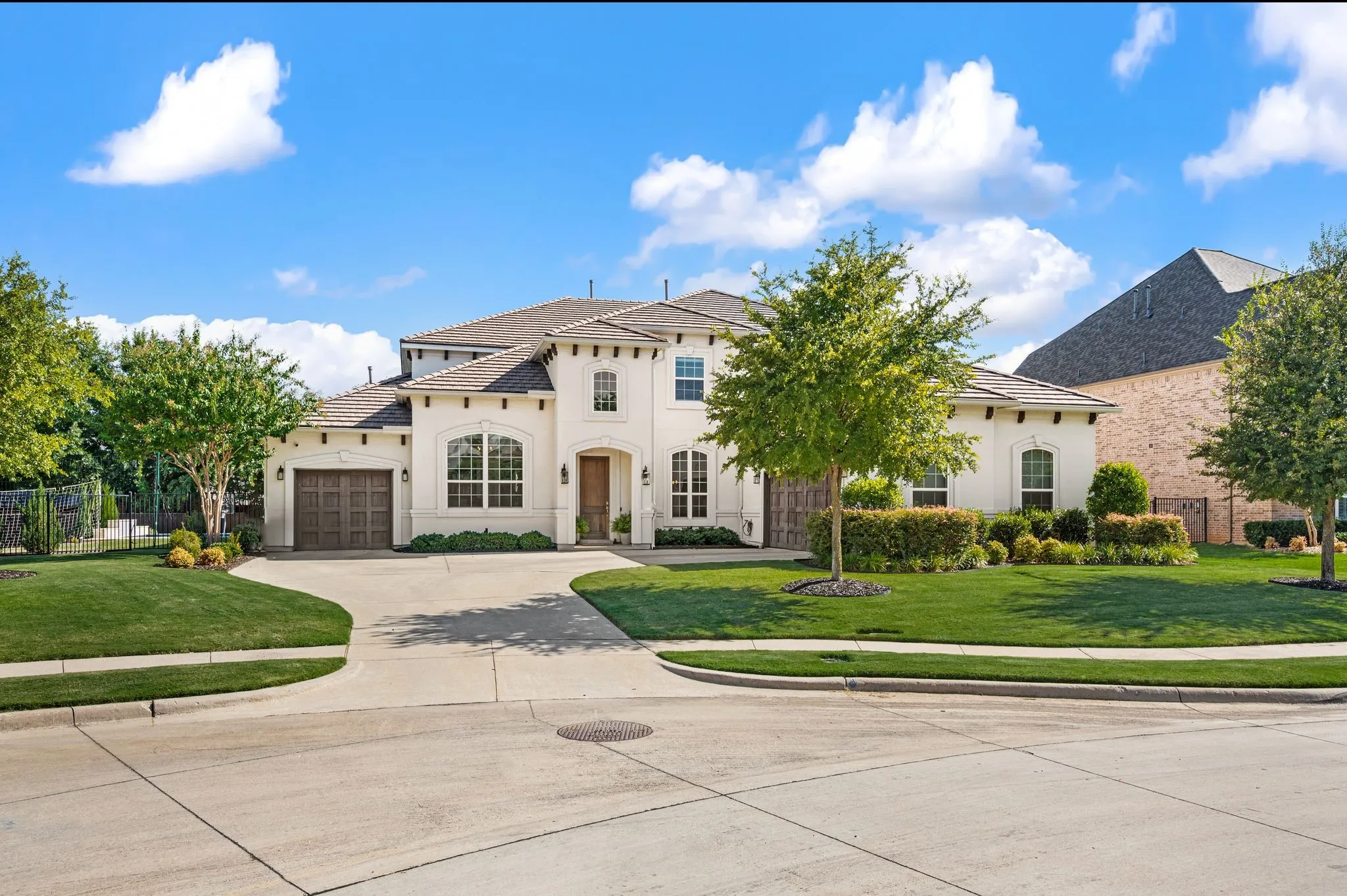 Stucco exterior with arched windows, a two-car garage, and a tiled roof